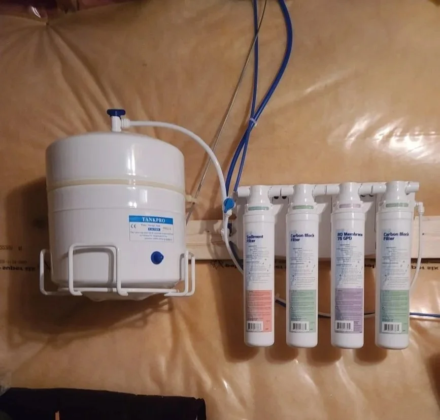 An image of an AquaFlo QCRO Reverse Osmosis Drinking Water System installed attached to a basement wall.