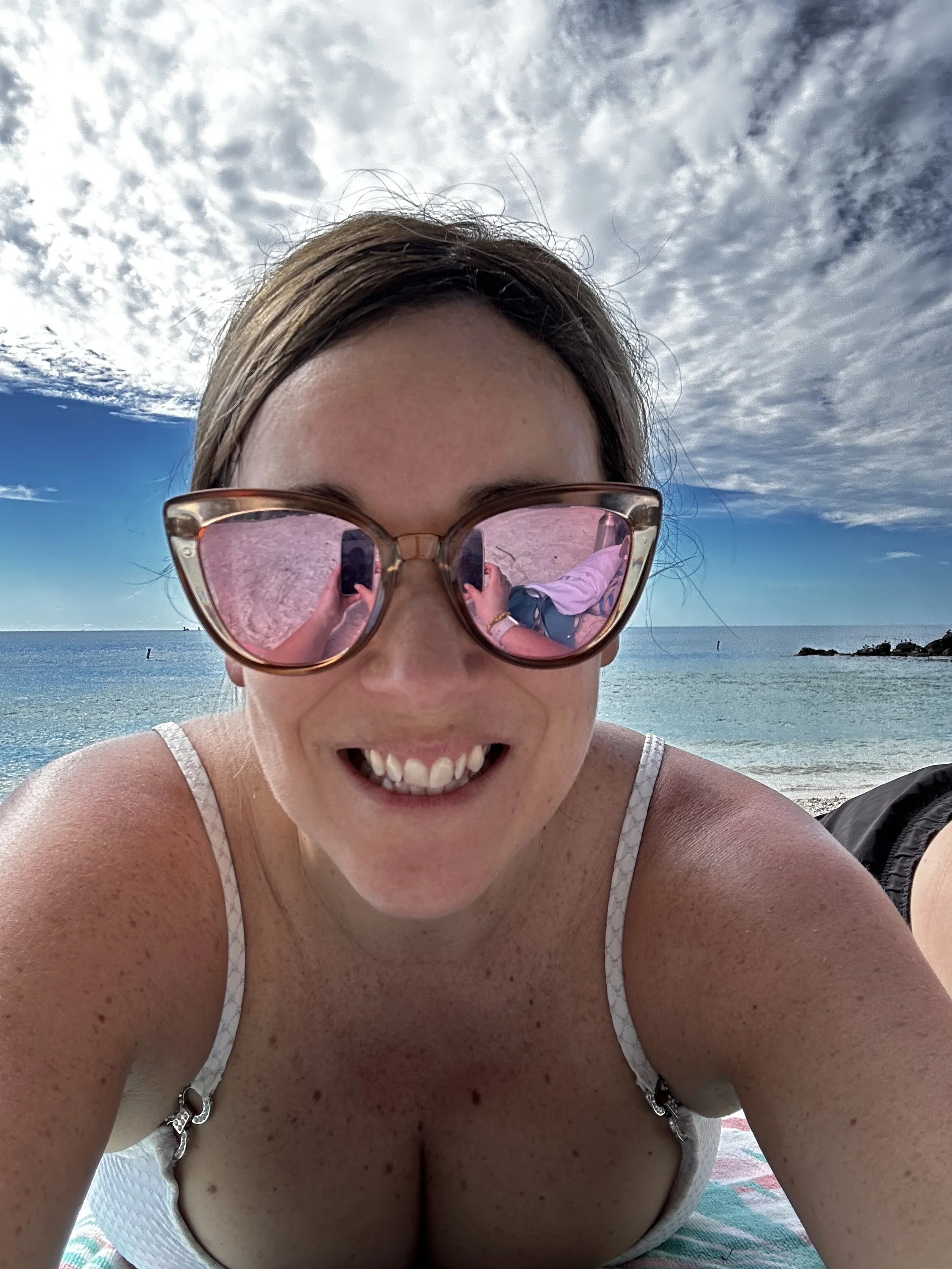 Amy lying on the beach with the sea in the background.