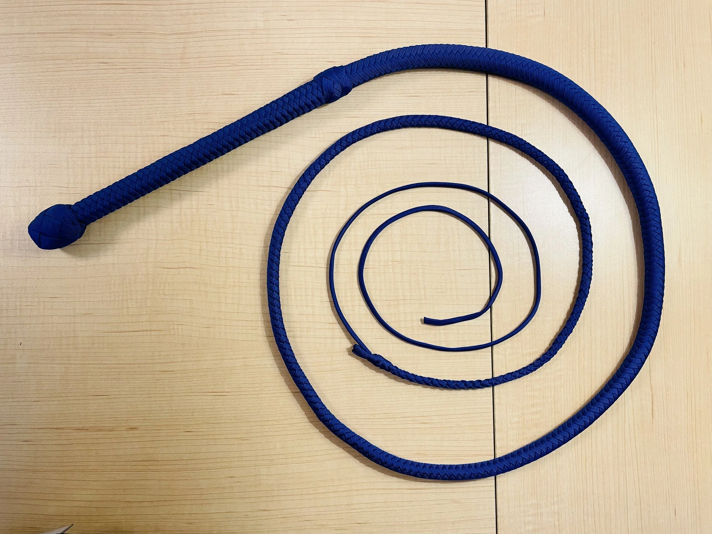 Various blue ropes arranged in a spiral pattern on a light wood surface.