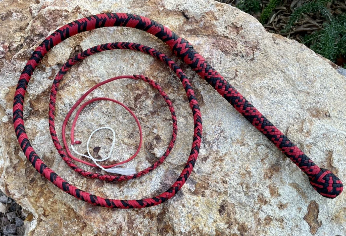 Three different lengths of red and black braided lanyards or cords on a large rock surface.