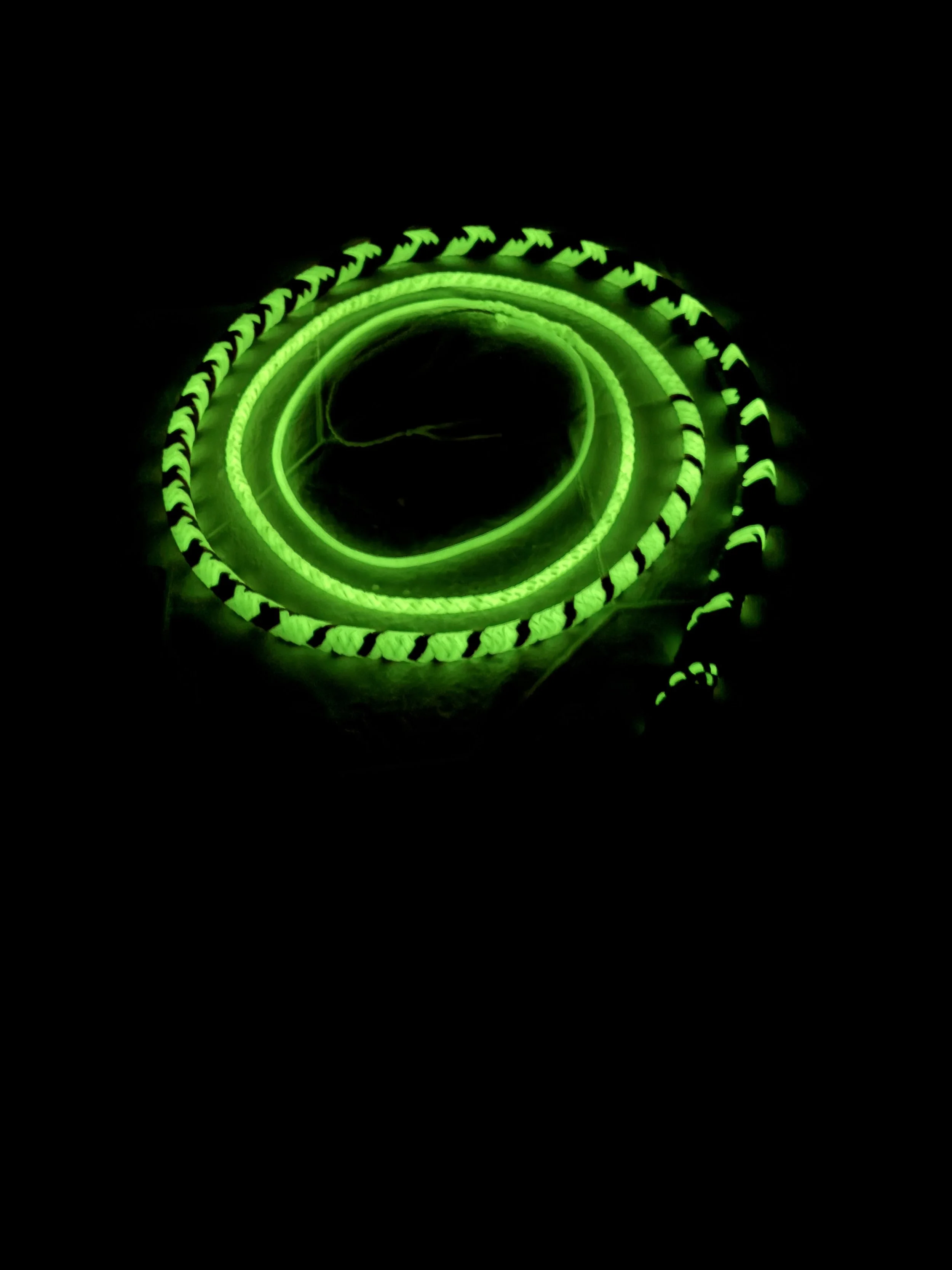Neon green glowing braided rope coil in dark.