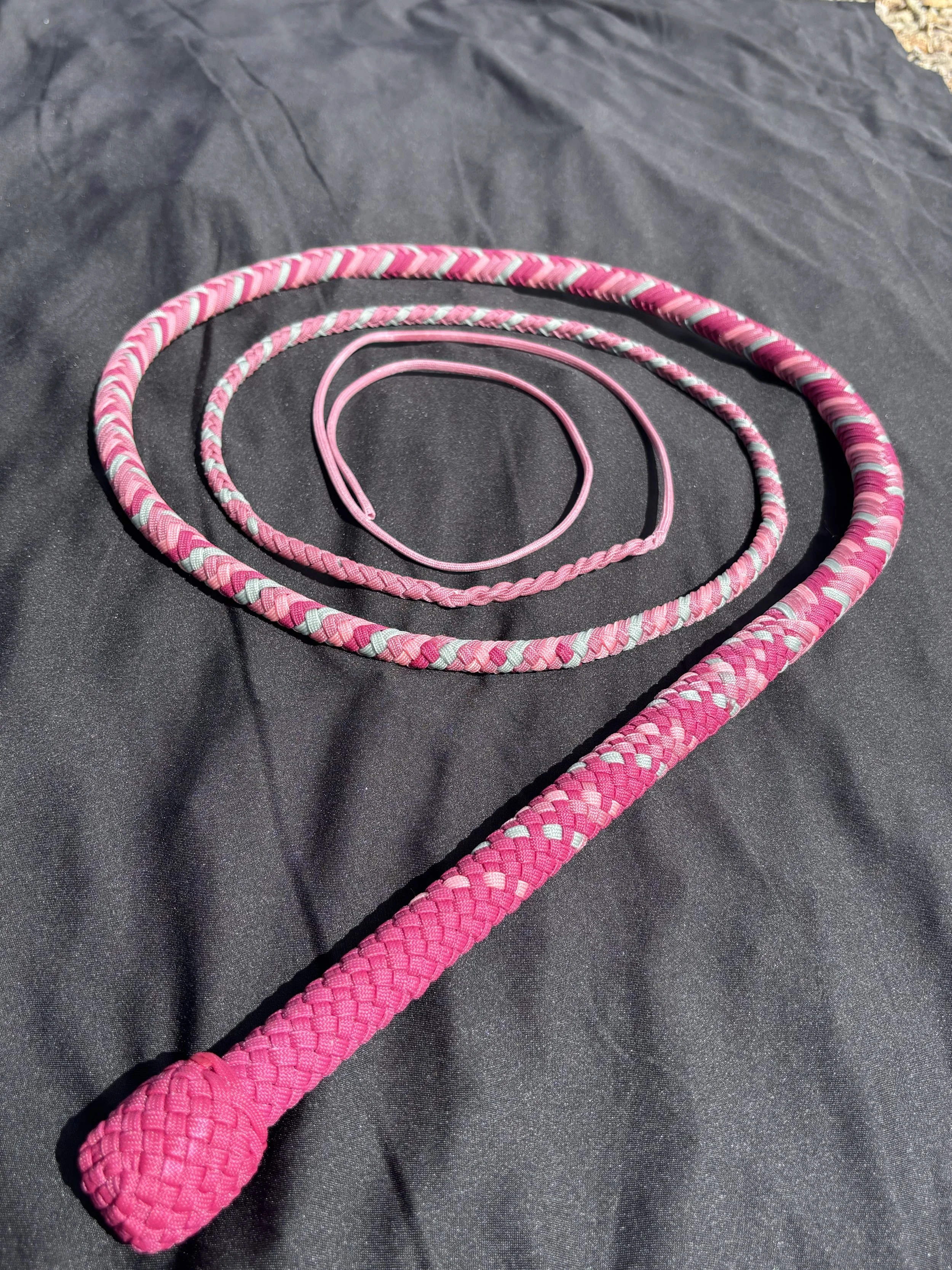 Three pink and gray braided ropes, with the largest rope forming a heart shape on a black background.