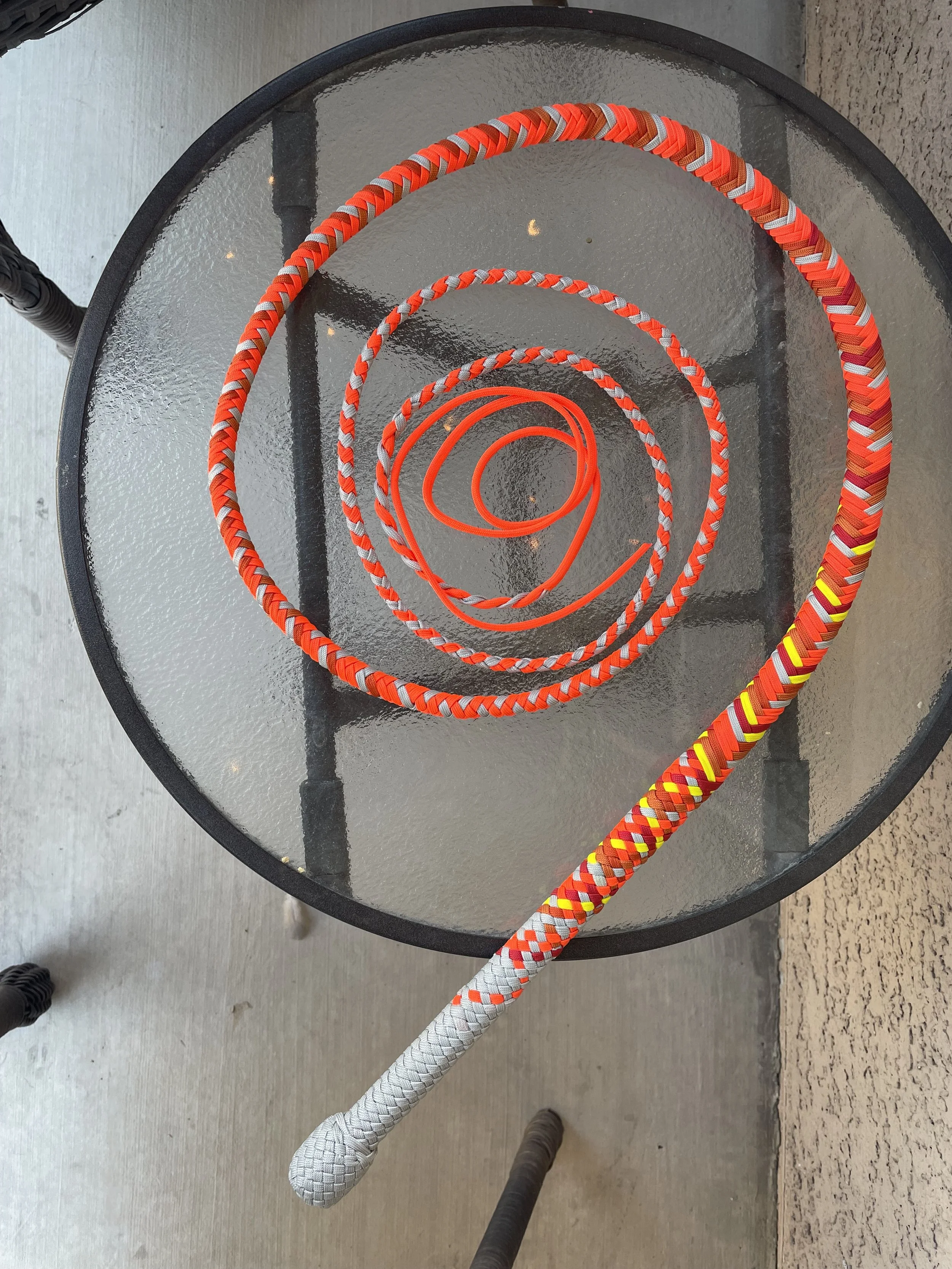 Colorful rope spirals on a glass-topped round outdoor table.