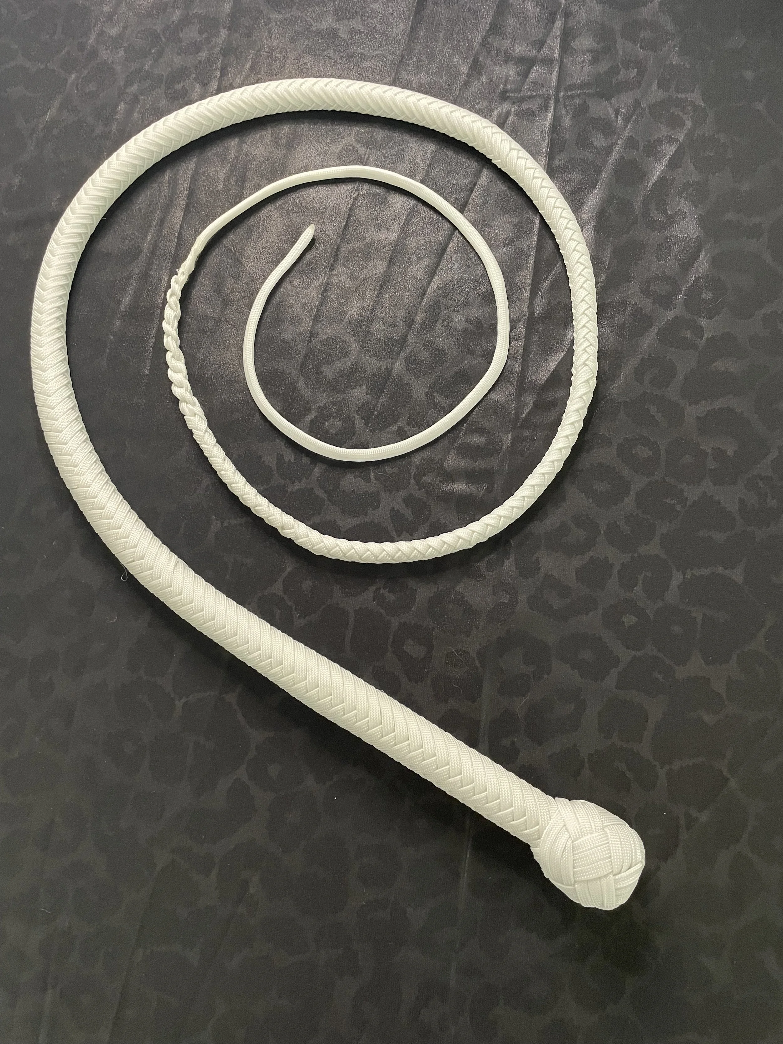 A collection of three white jump ropes of varying sizes, arranged on a dark textured surface.