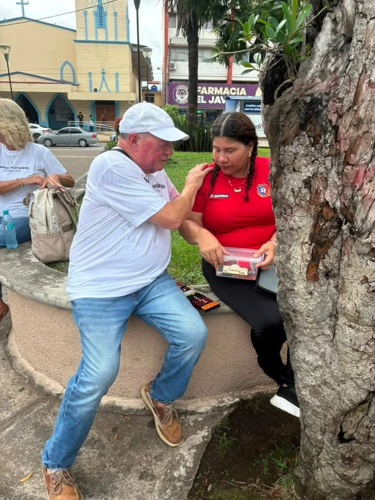 Rick Bonfim Ministries team member praying with a woman during street outreach on the Panama mission trip.