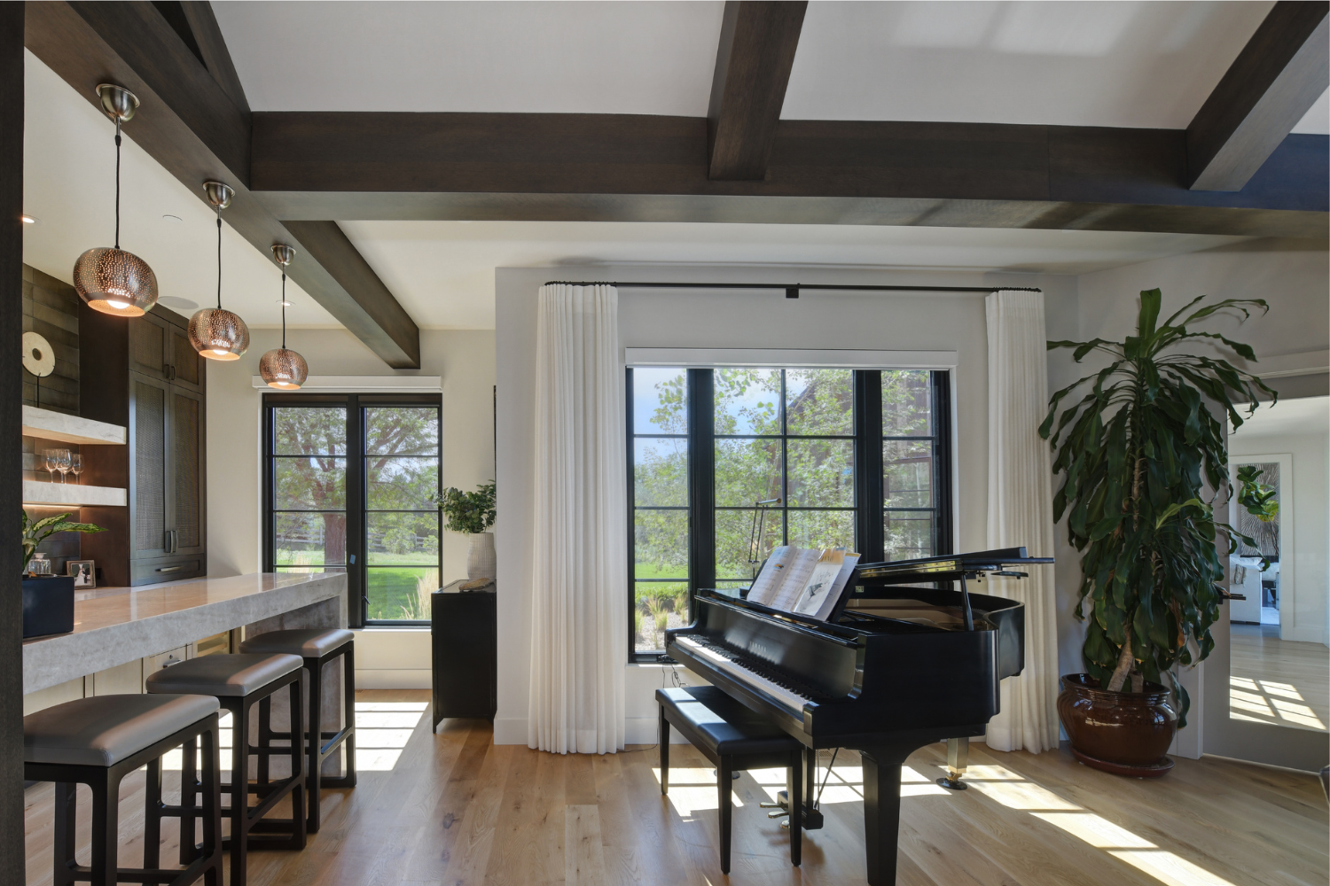 Open-concept interior with piano and bar area showing material continuity, natural light, and cohesive flow between spaces