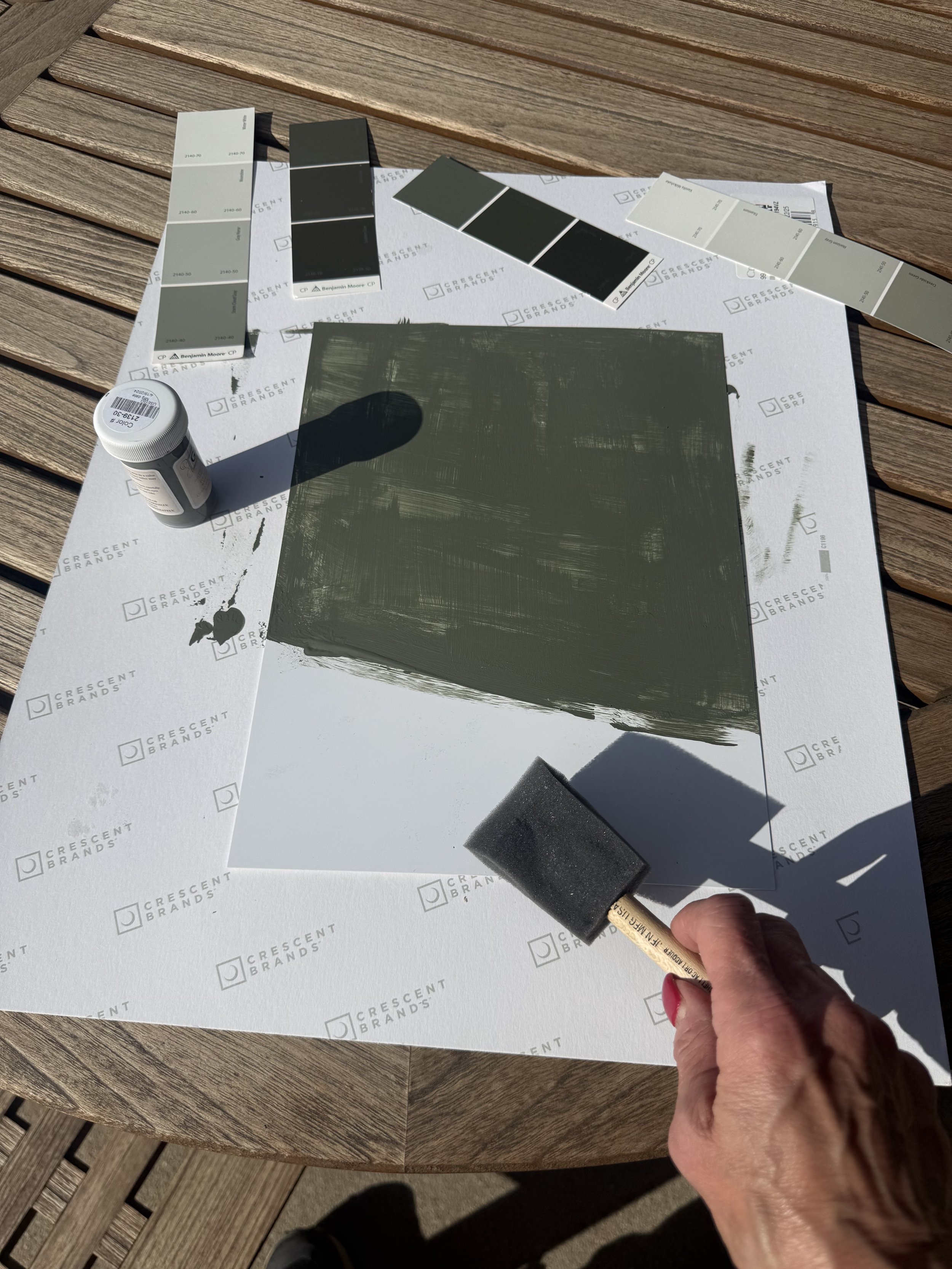 Designer comparing neutral paint samples in natural daylight alongside finish selections.