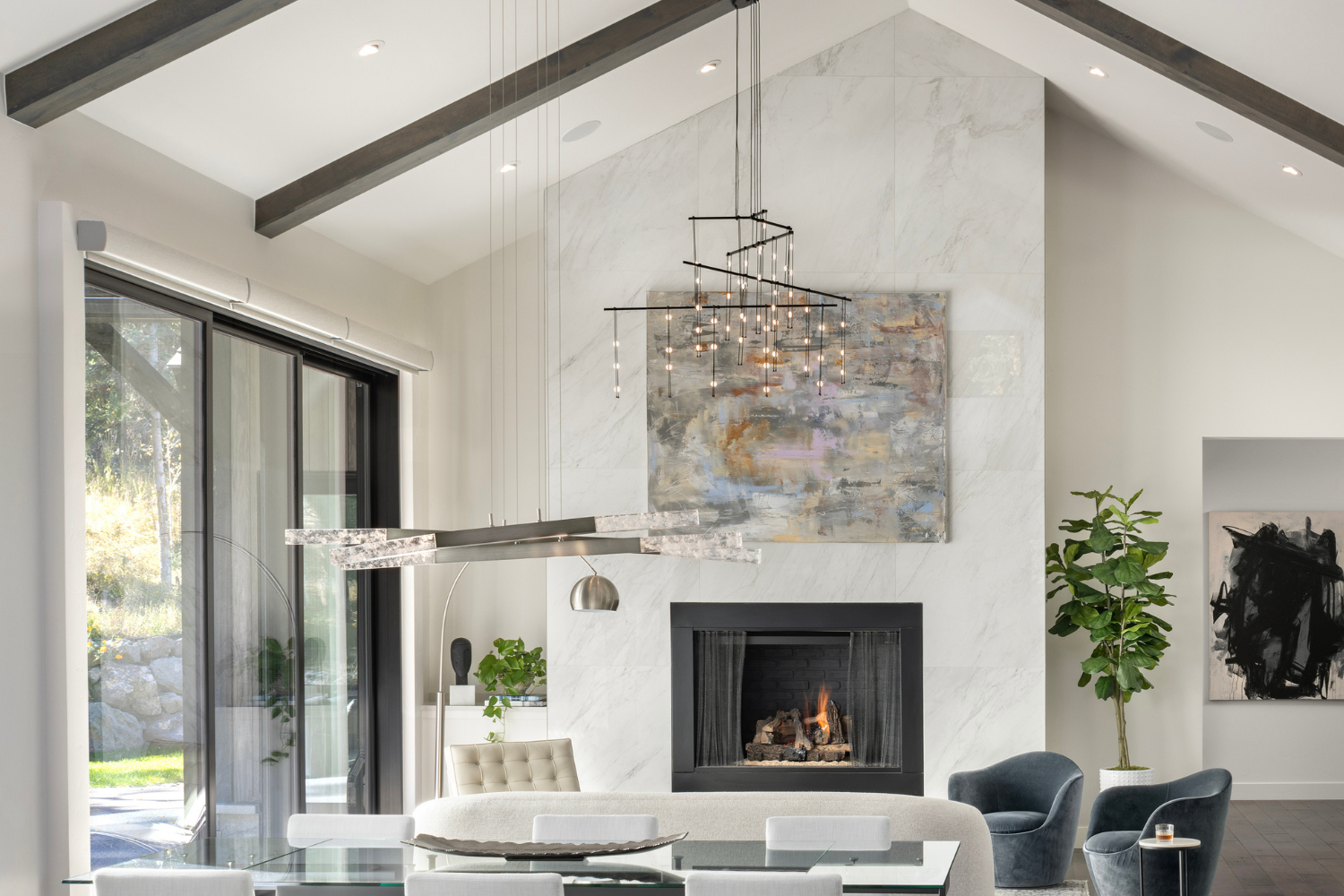 Open-concept living and dining space with marble fireplace wall, vaulted ceiling, and integrated lighting design