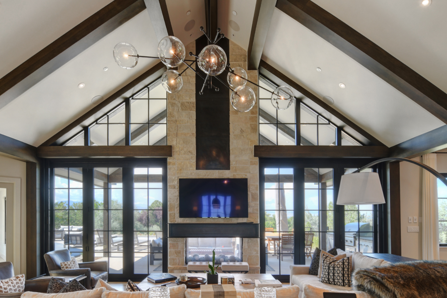 Living room in a custom Colorado home with exposed beams, statement chandelier, and layered materials creating a high-end, cohesive interior