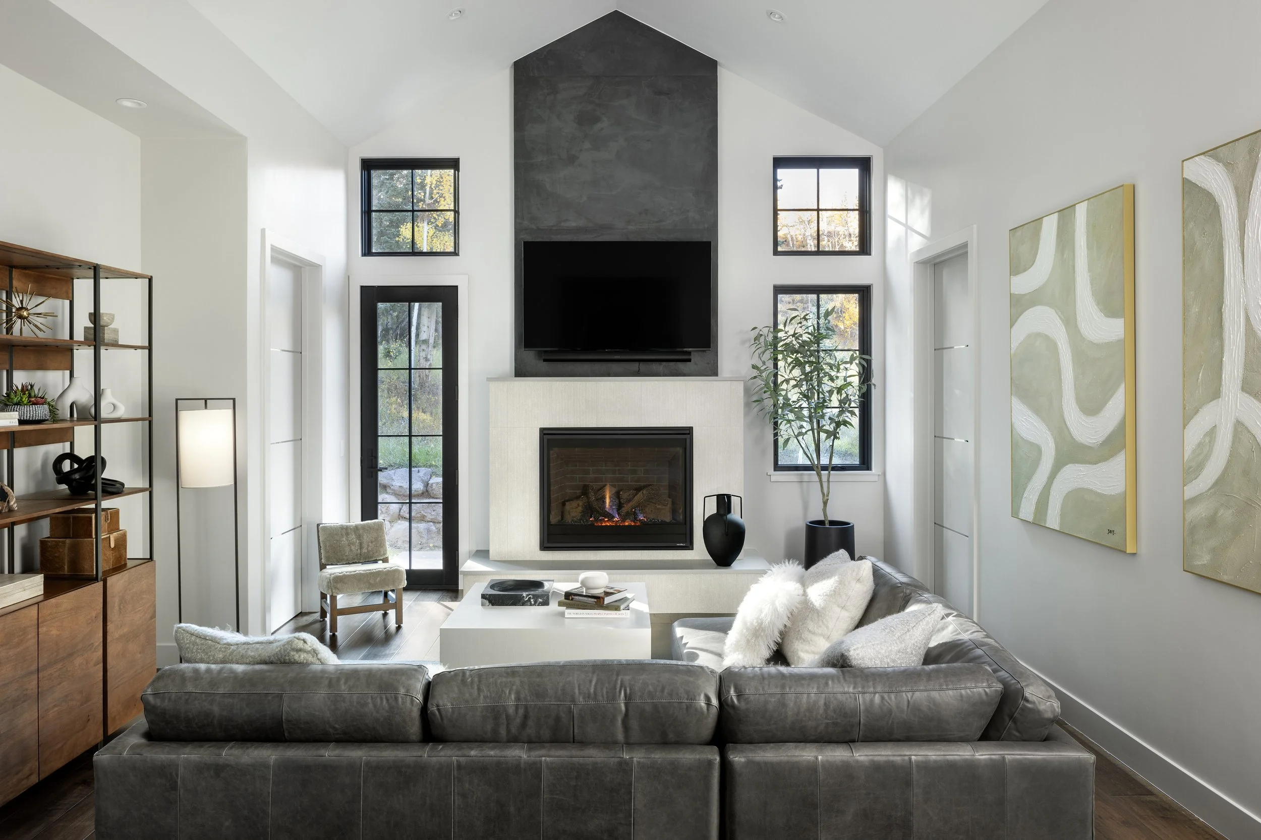 Colorado  living room with modern fireplace, leather sectional, warm wood furnishings and contemporary artwork