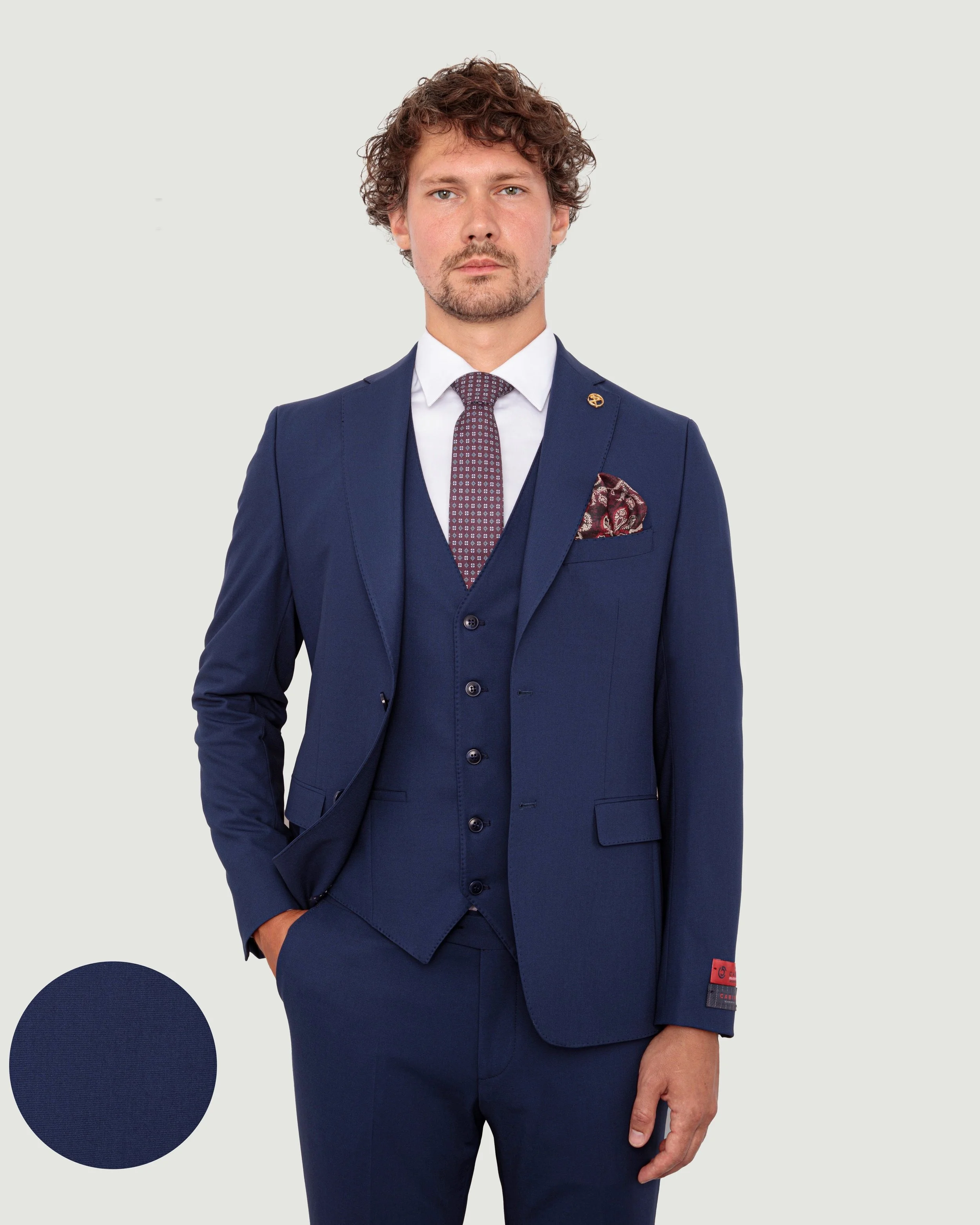 Men's navy blue suit, white shirt, patterned tie, and pocket square.