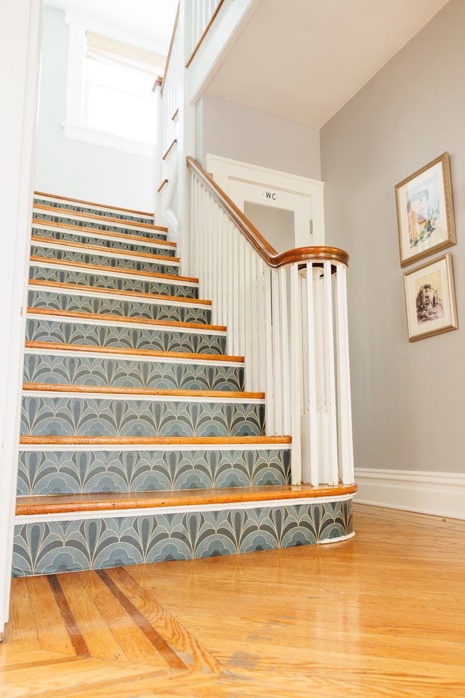 A classic wooden staircase with decorative, patterned carpet runners leading up to a well-lit upper level, adjacent to a small bathroom labeled "w.c." in a cozy residential interior.