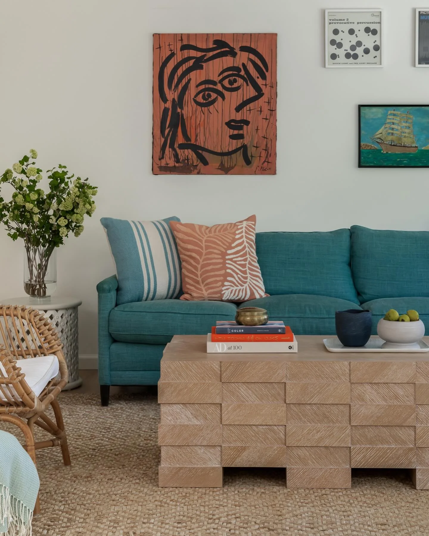 A coastal home built for the long weekend, whether the sky cooperates or not. Teal linen anchors the space. Warm terracotta and washed indigo layer in through the pillows and the gallery wall. Underfoot, a jute weave and a rattan chair keep everythin