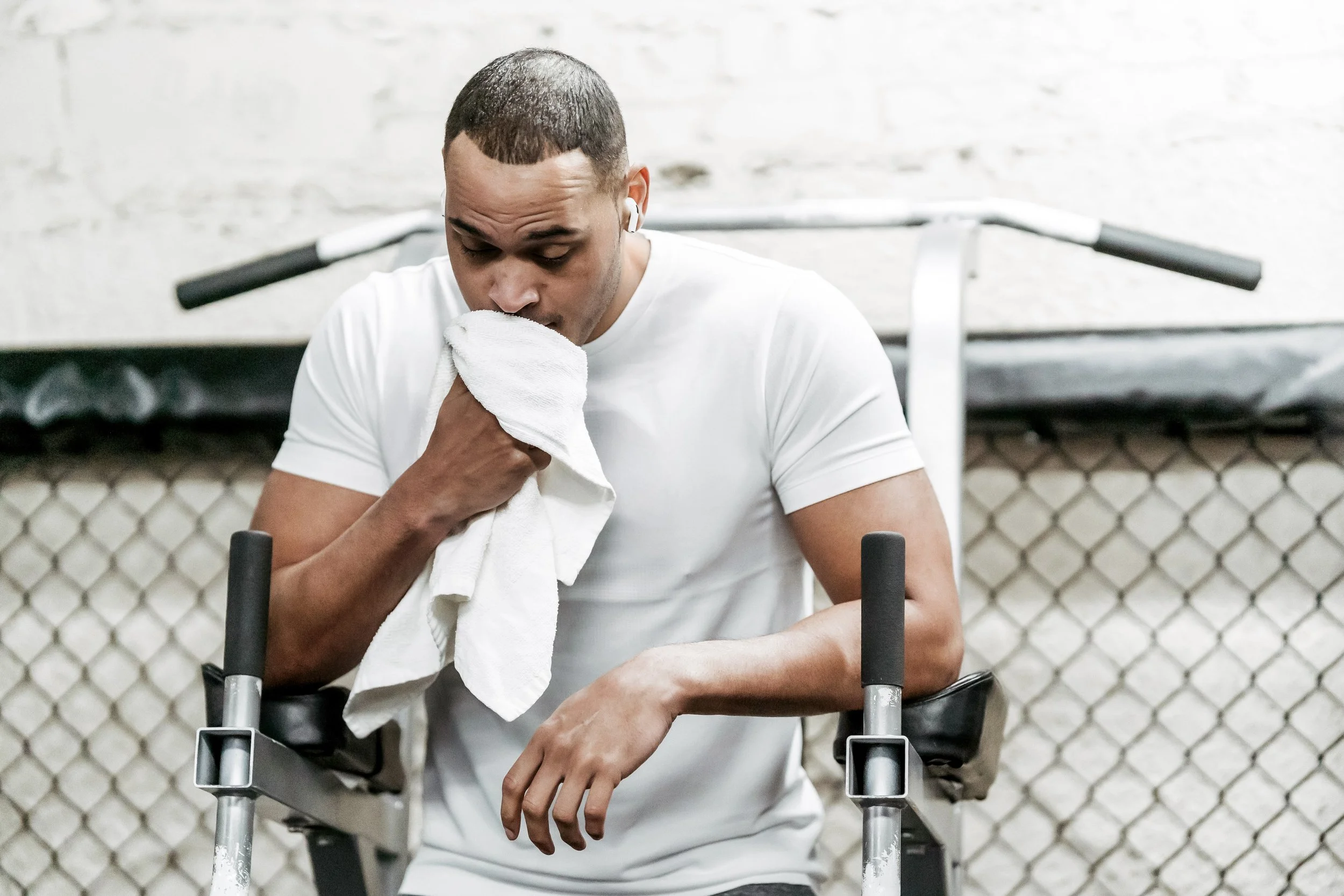 Athlete leaning on crutches, wiping sweat with a towel in a gym or training facility.