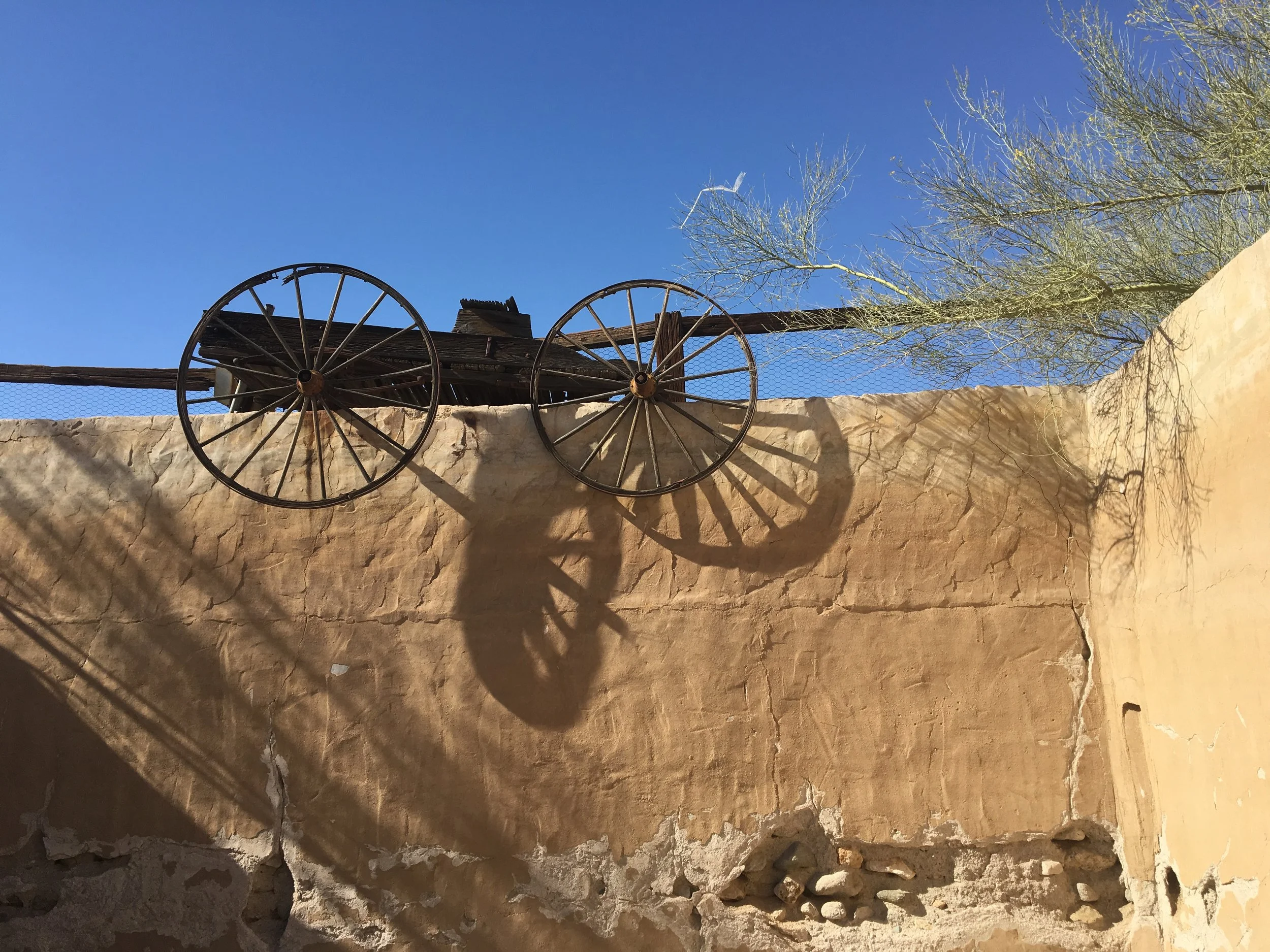 wagon-wheels-on-adobe-wall-desert-center.JPG