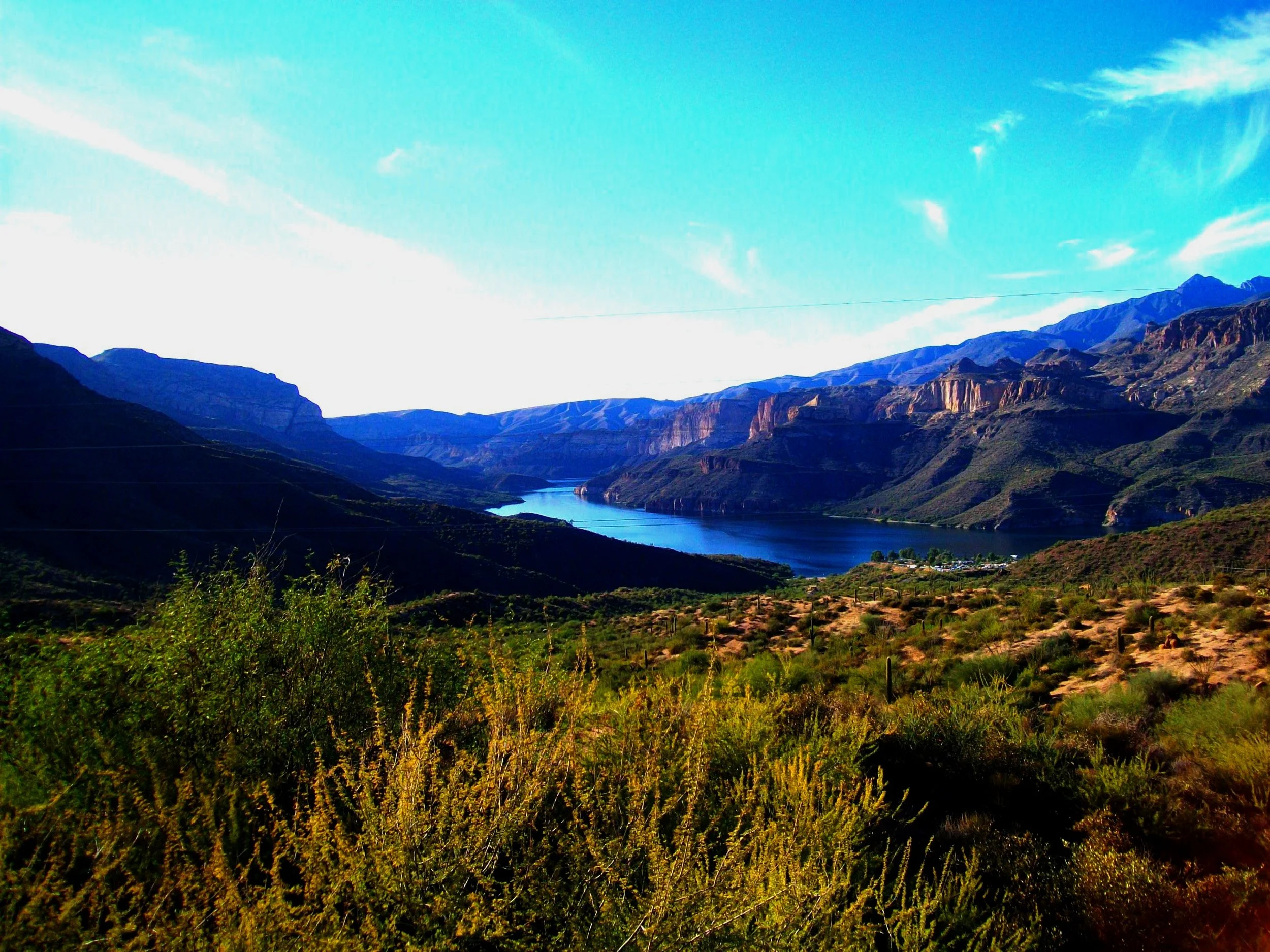 Scenic overlook of Apache Lake along the Apache Trail showing the winding lake between towering desert mountains.