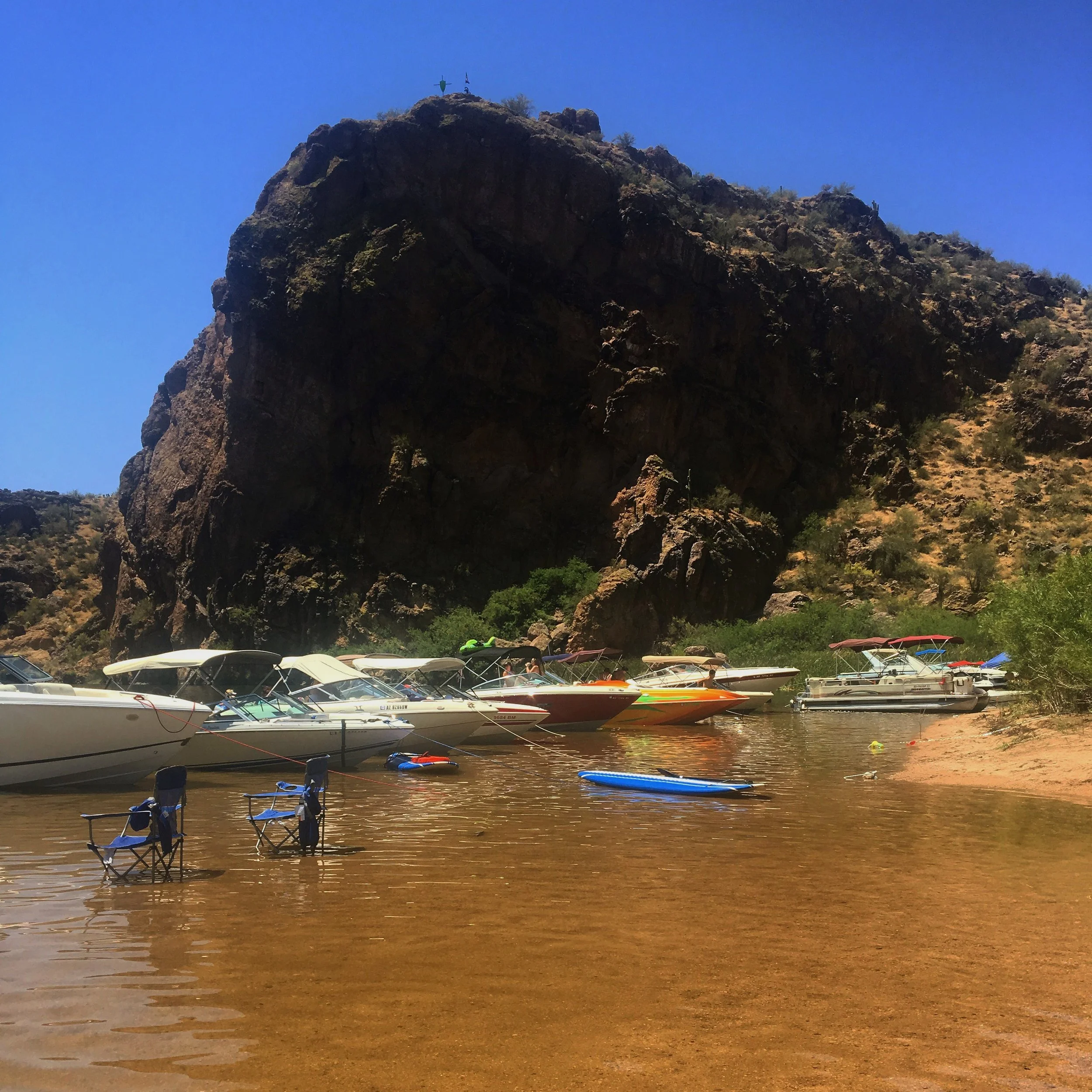 Boats floating on Saguaro Lake with rugged desert mountains rising in the background near the Superstition wilderness.