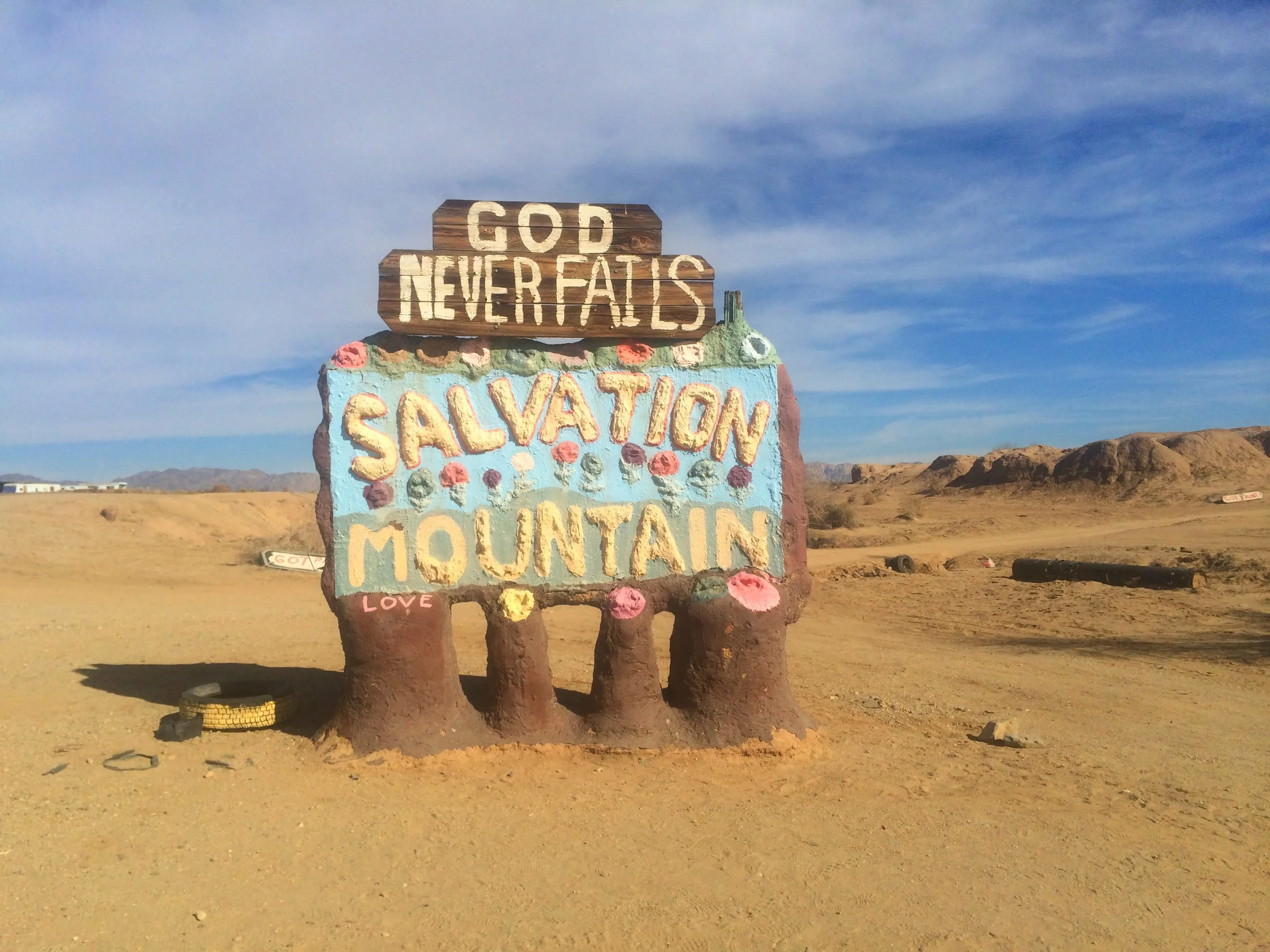 Welcome sign for Salvation Mountain standing in the desert near Slab City, California.