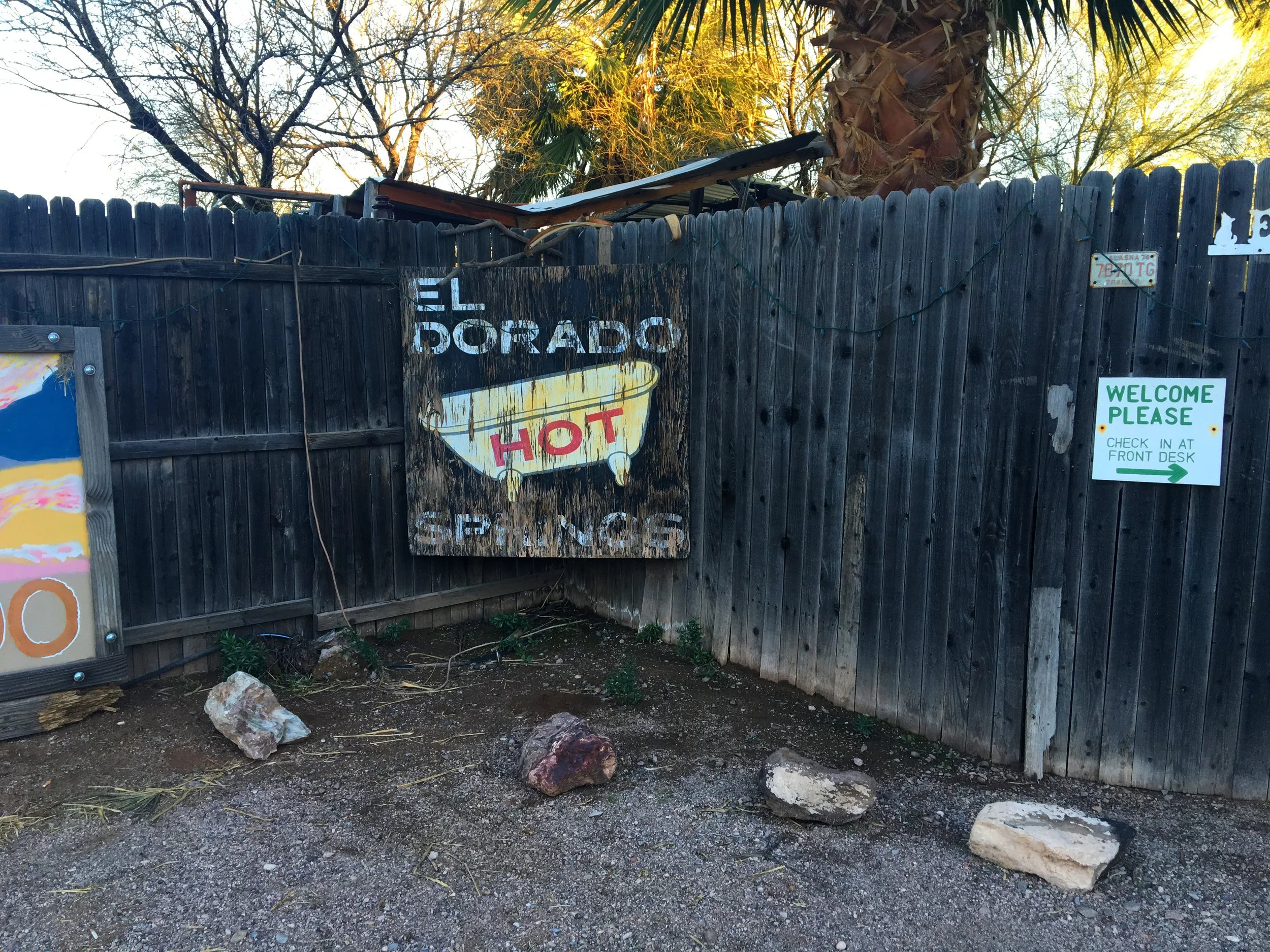 Rustic wooden fencing and rustic sign with desert landscaping at El Dorado Hot Springs in Arizona’s Sonoran Desert.