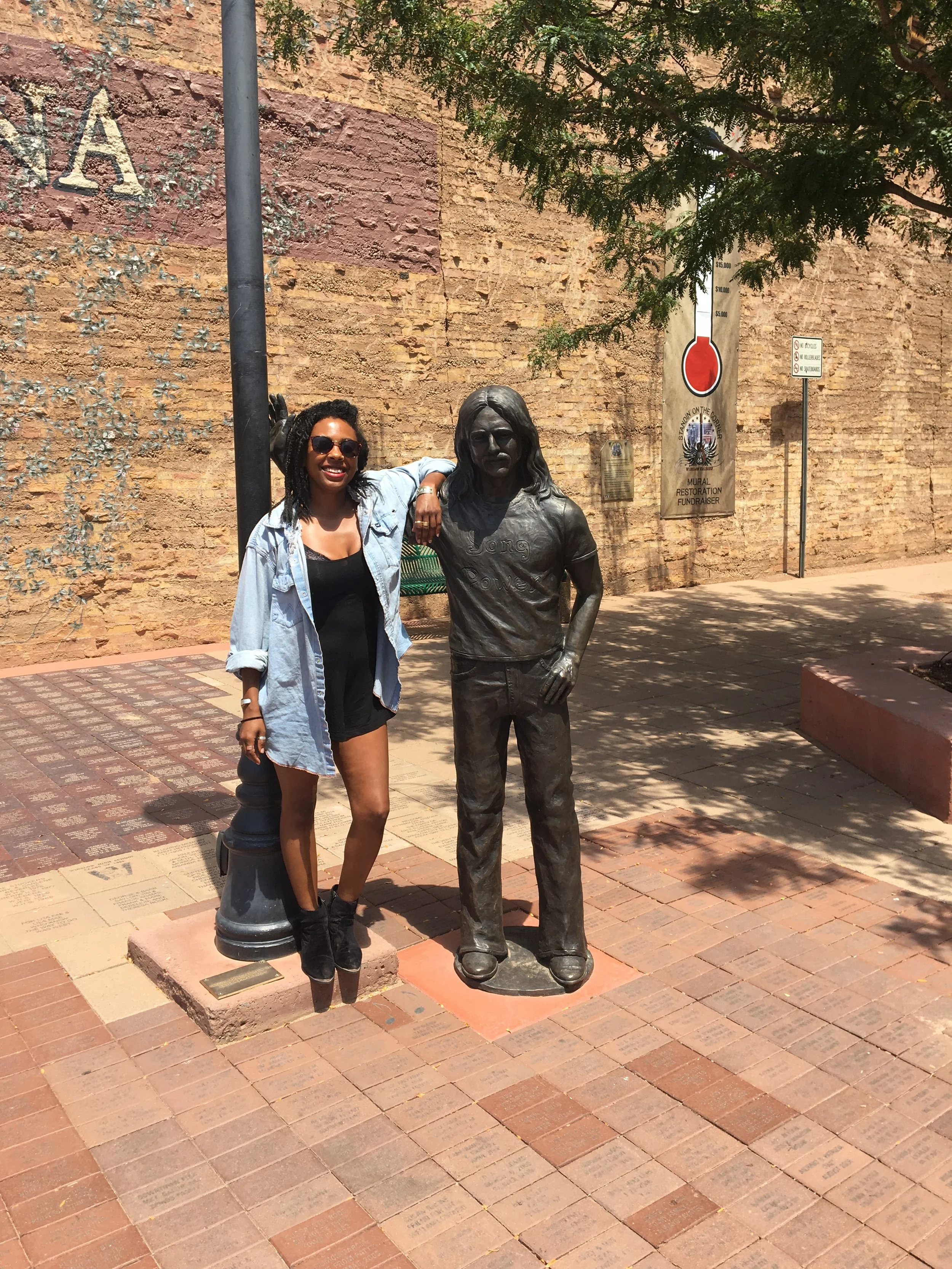 Traveler standing next to the statue of Glenn Frey at the Standin’ on the Corner Park in Winslow, Arizona