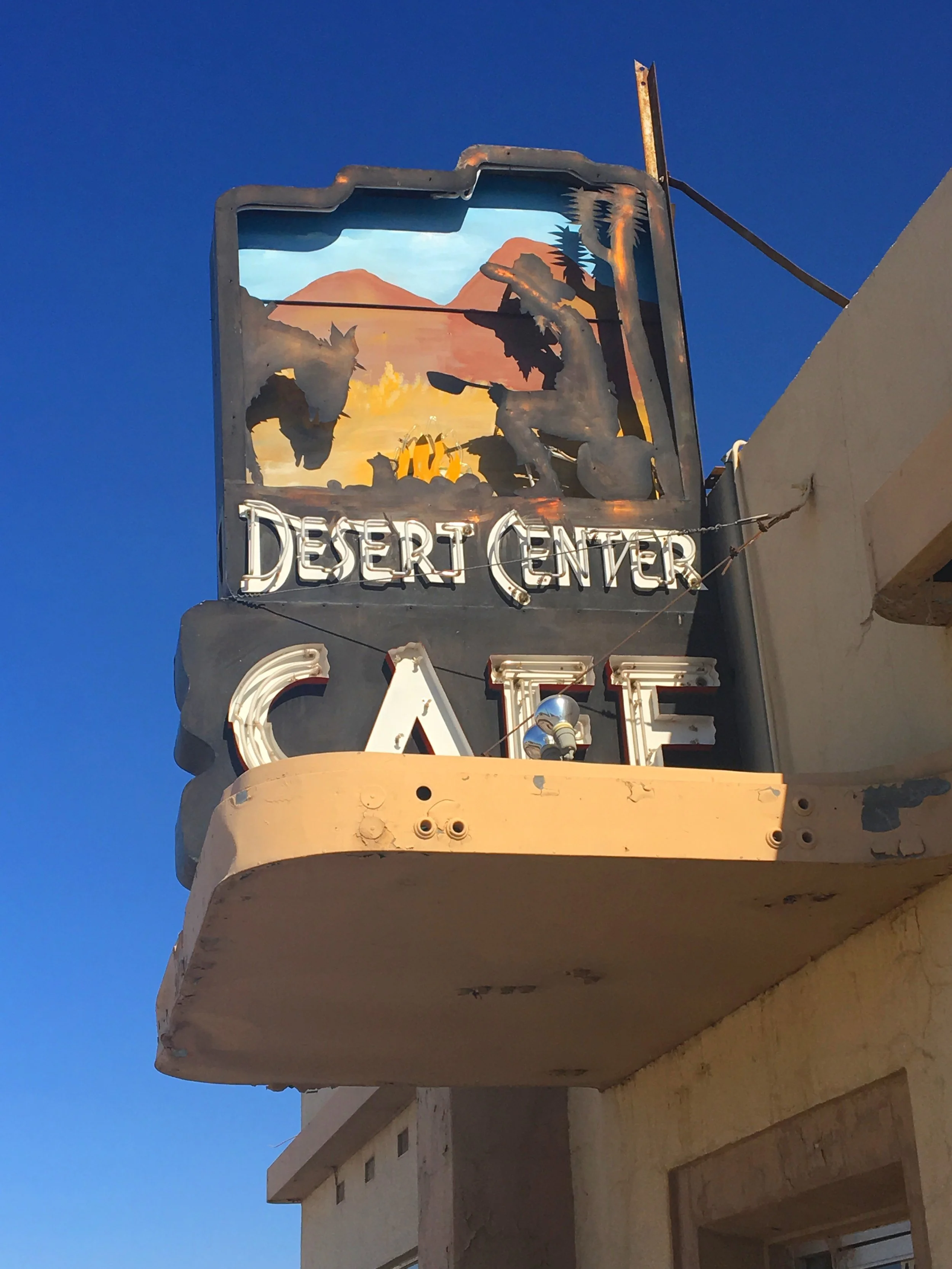 Detailed view of the vintage Desert Center Cafe roadside sign against a clear desert sky in California.
