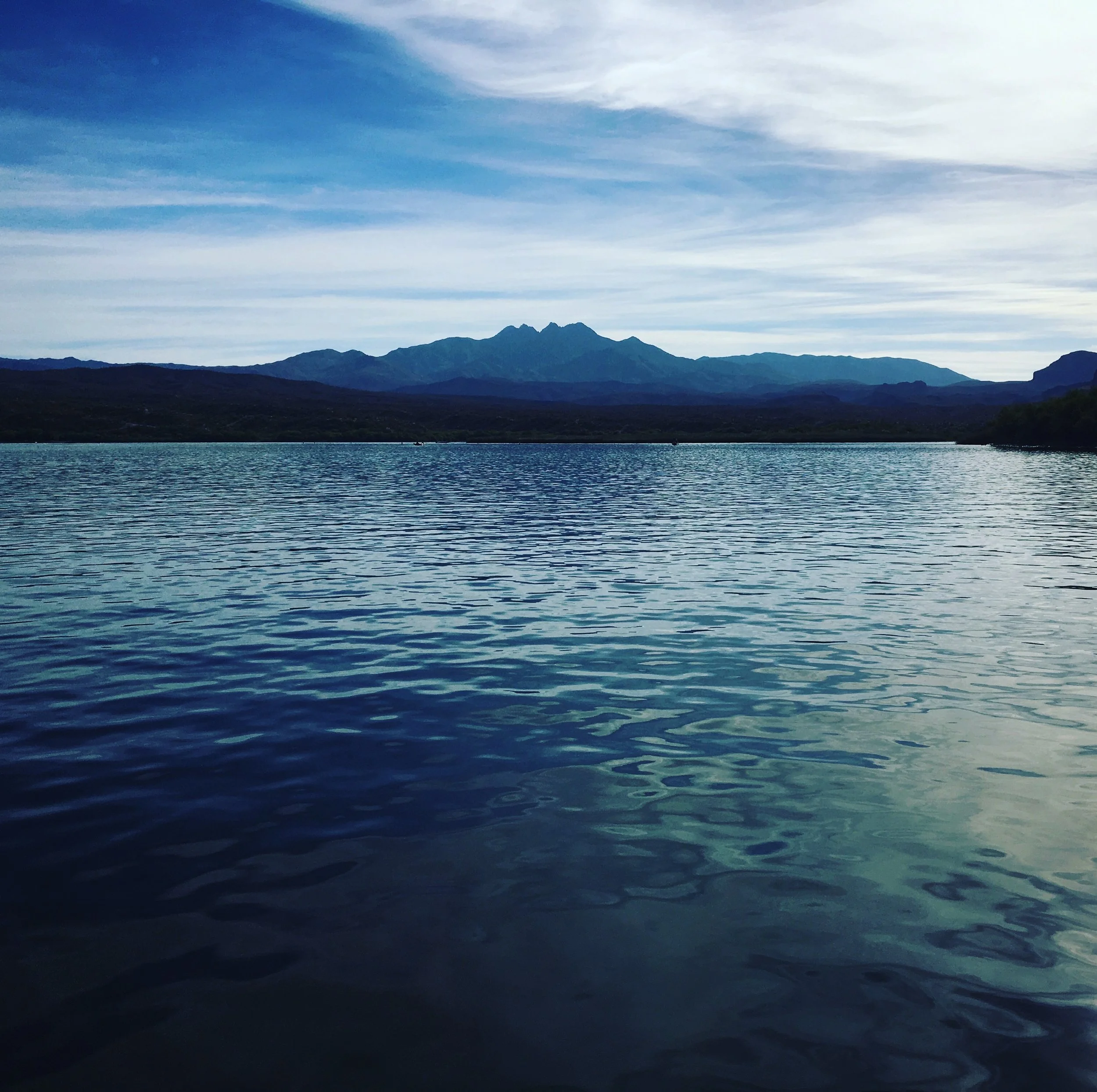 Wide view of Four Peaks rising above the blue waters of Saguaro Lake in the Arizona desert.