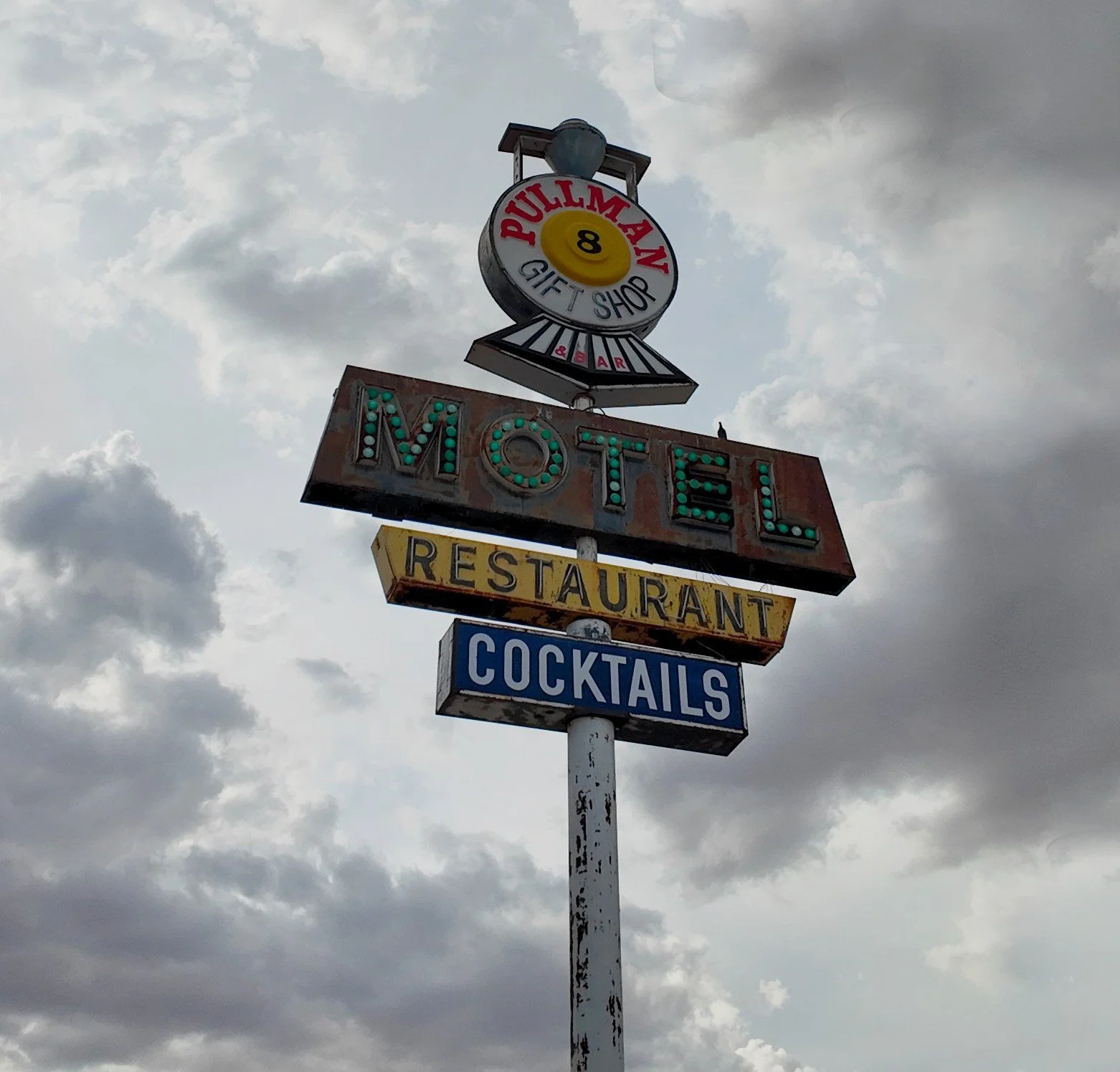 Weathered vintage Pullman Motel, Restaurant, and Cocktails roadside sign beneath a cloudy desert sky near Interstate 8 and Highway 84 in Stanfield, Arizona.