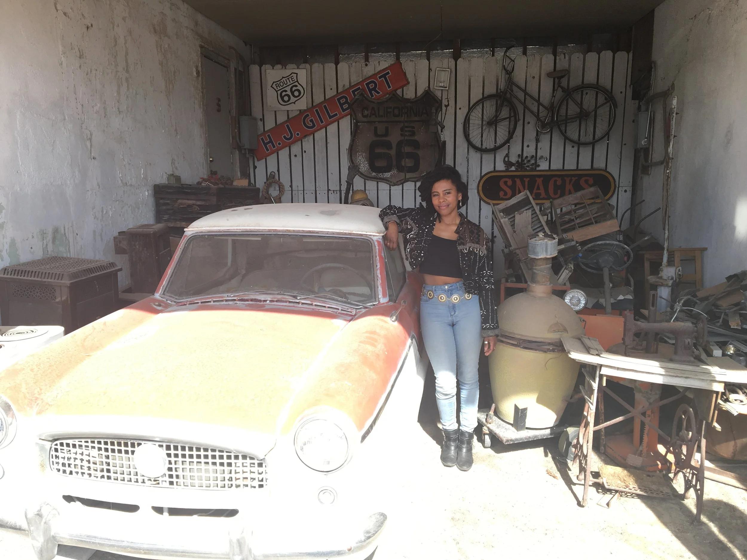 Visitor standing beside a classic car at the Route 66 Motel in Barstow, California.