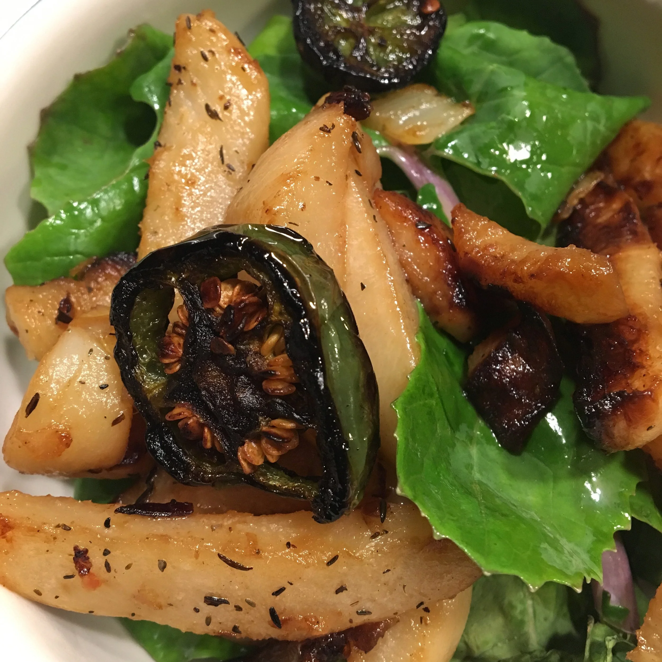 Roasted rutabaga fries served with leafy greens and sliced jalapeños.