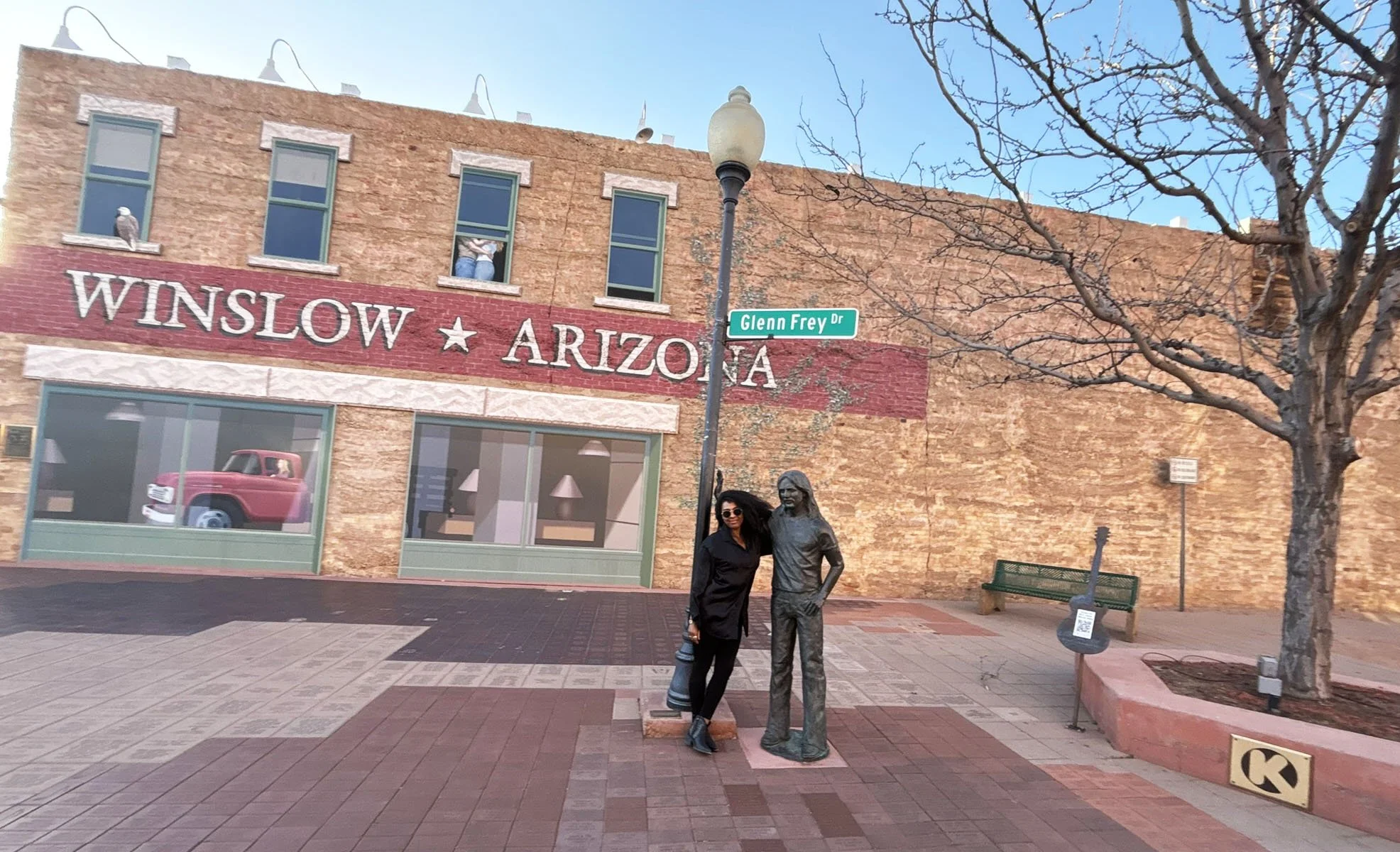 Woman standing next to the Standin’ on the Corner statue of Glenn Frey in Winslow, Arizona.
