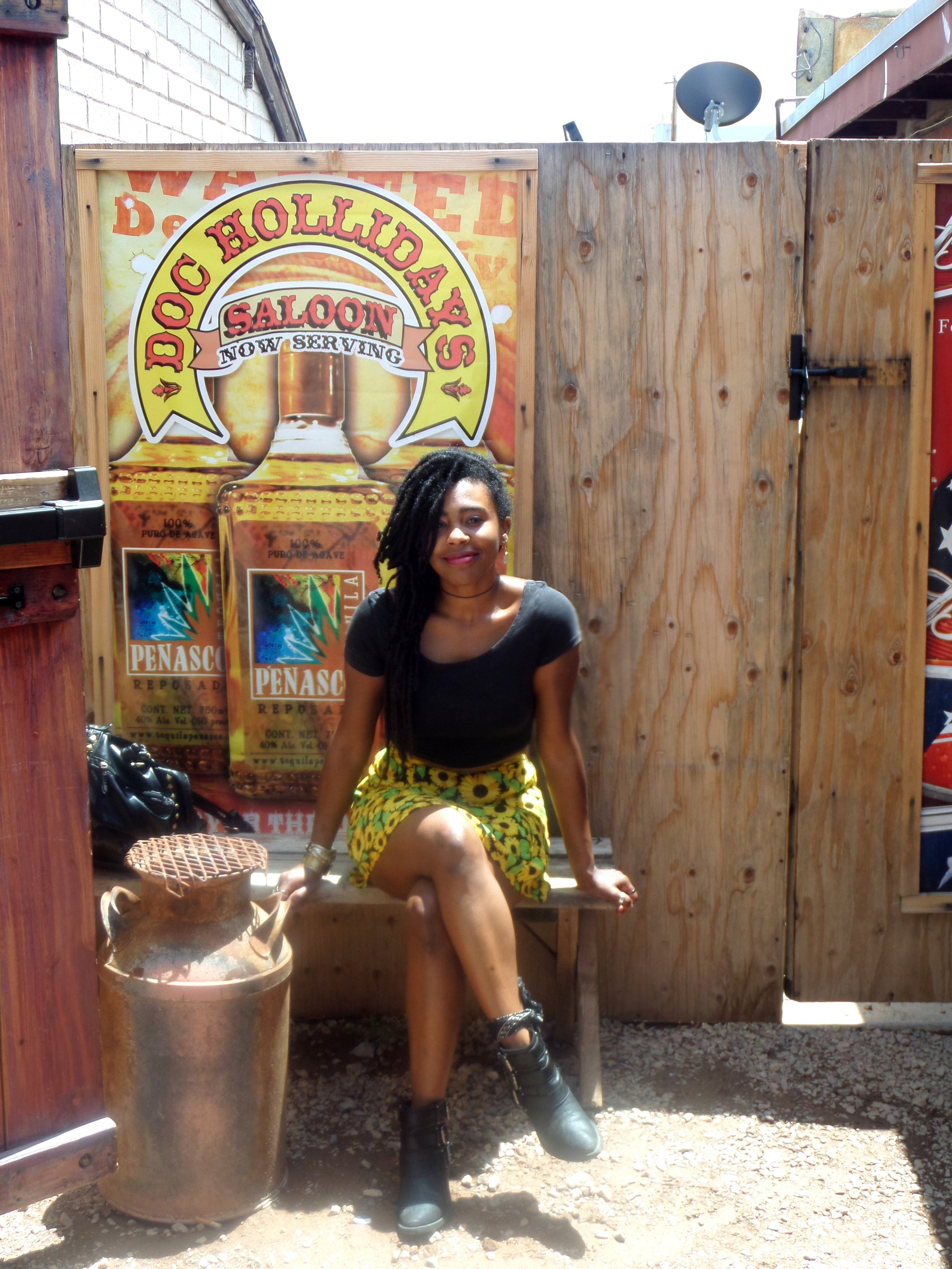 Visitor sitting in front of a Doc Holliday sign in Tombstone, Arizona