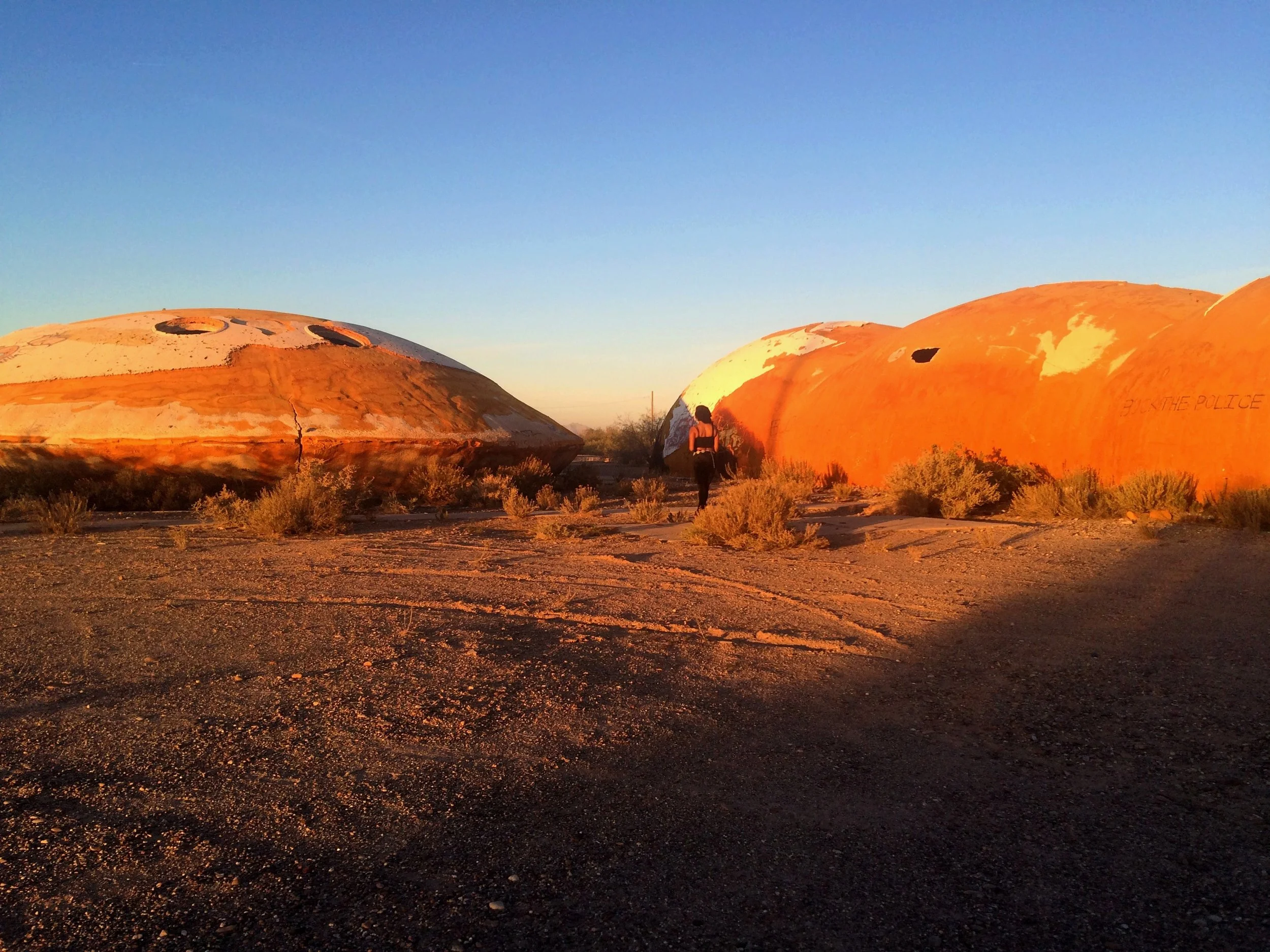Wide shot of the Domes of Casa Grande silhouetted against a desert sunset sky.