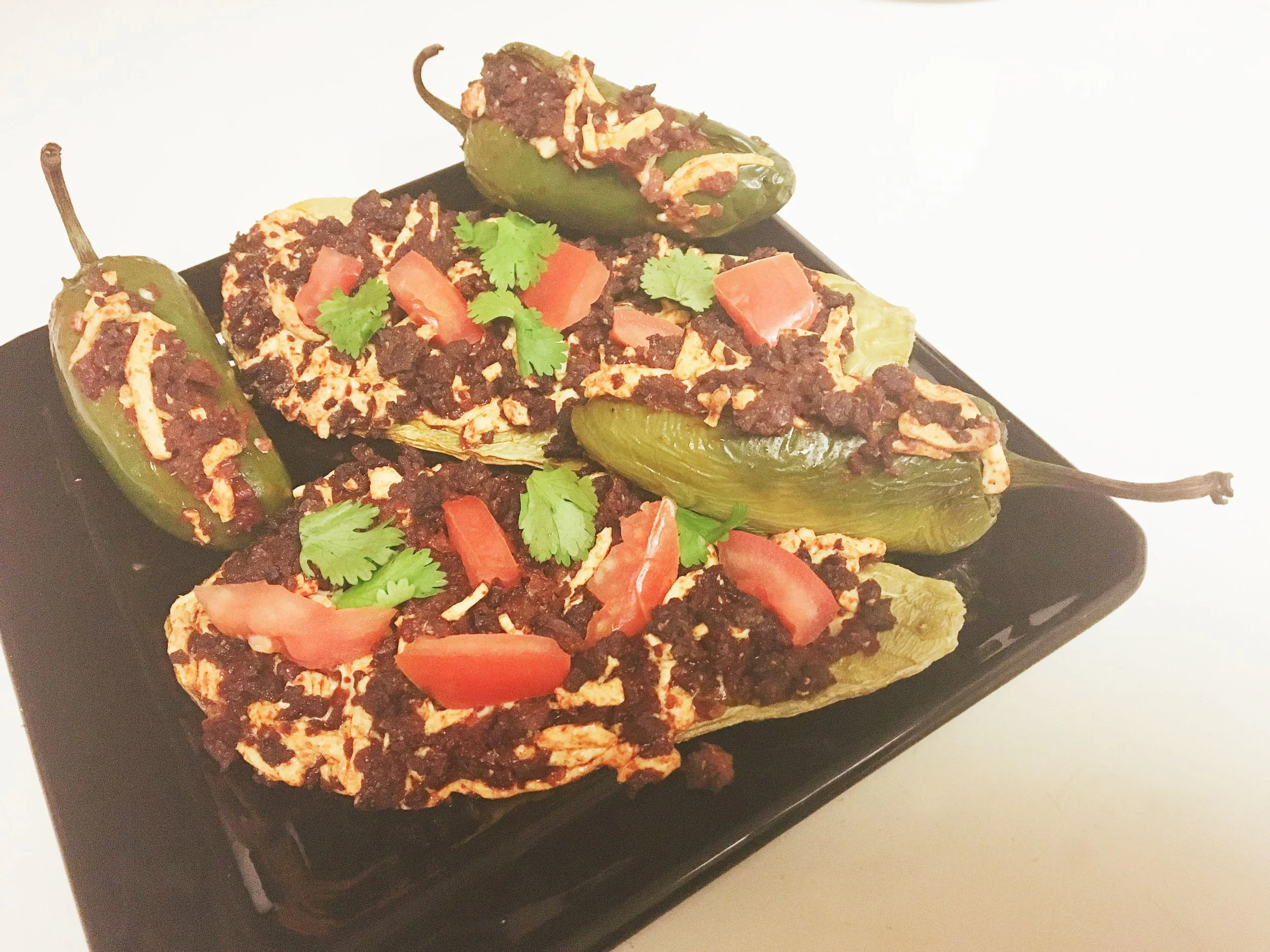 Two nopal cactus boats filled with peppers, vegetables, vegan beef, and melted vegan cheese.