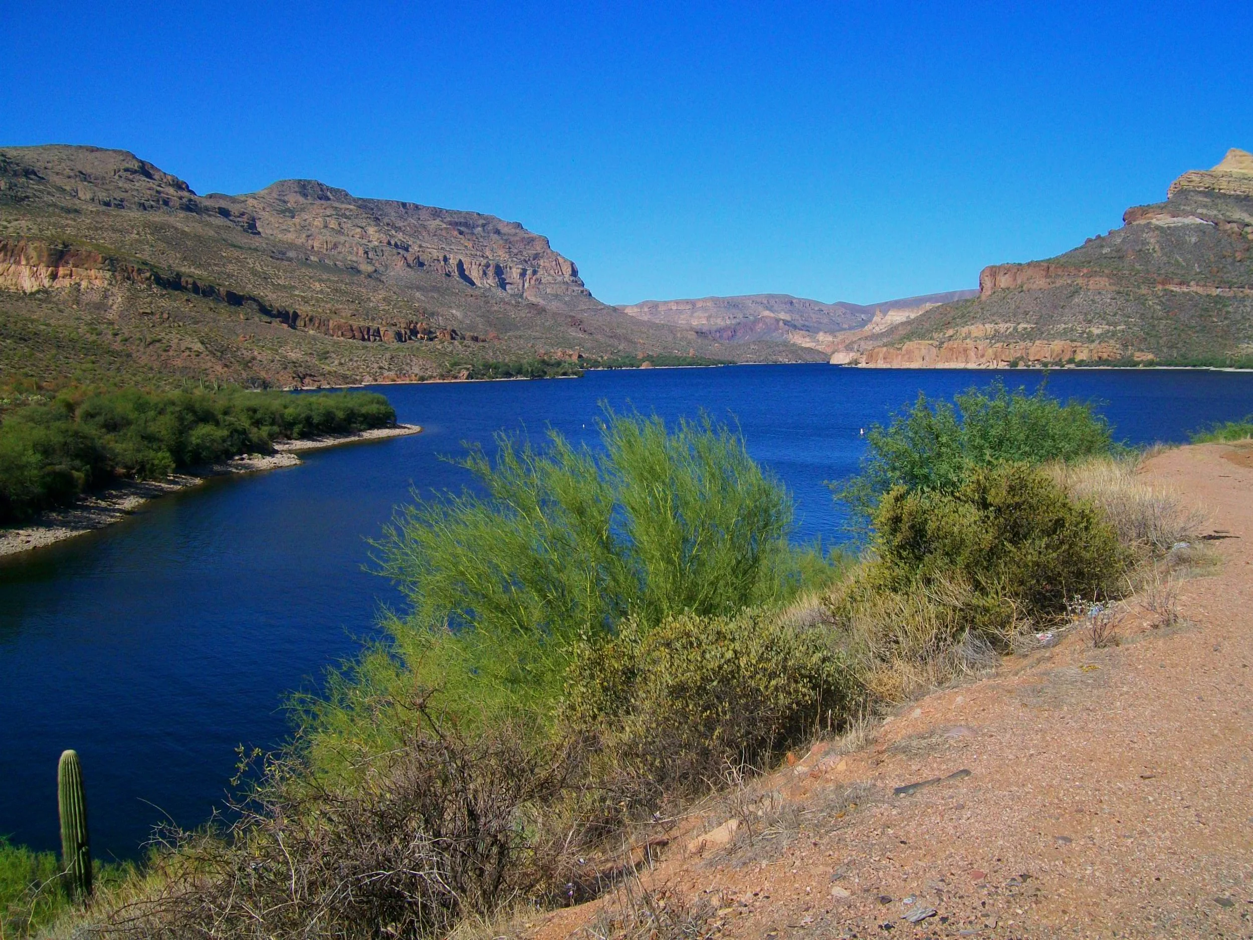 Panoramic view overlooking Apache Lake with deep blue water surrounded by rugged desert mountains and canyon walls.