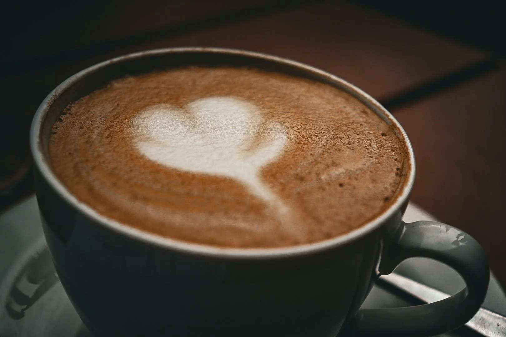 A black coffee mug with foam art in the shape of a heart on top of a latte