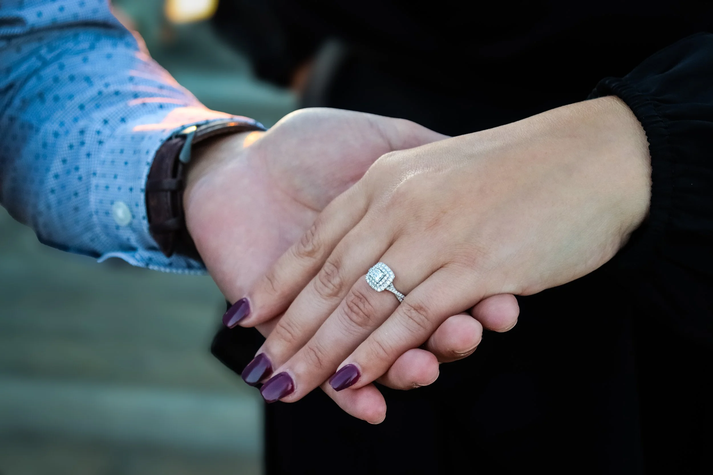 Close-up of two people shaking hands, one wearing a diamond ring on the finger, with a focus on the hands and jewelry.