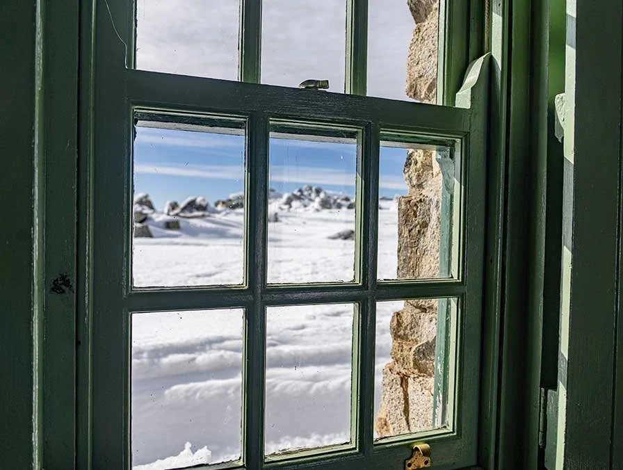 Snowy Main Range landscape through an alpine hut window