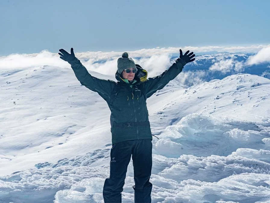 Standing on a Main Range summit, arms raised