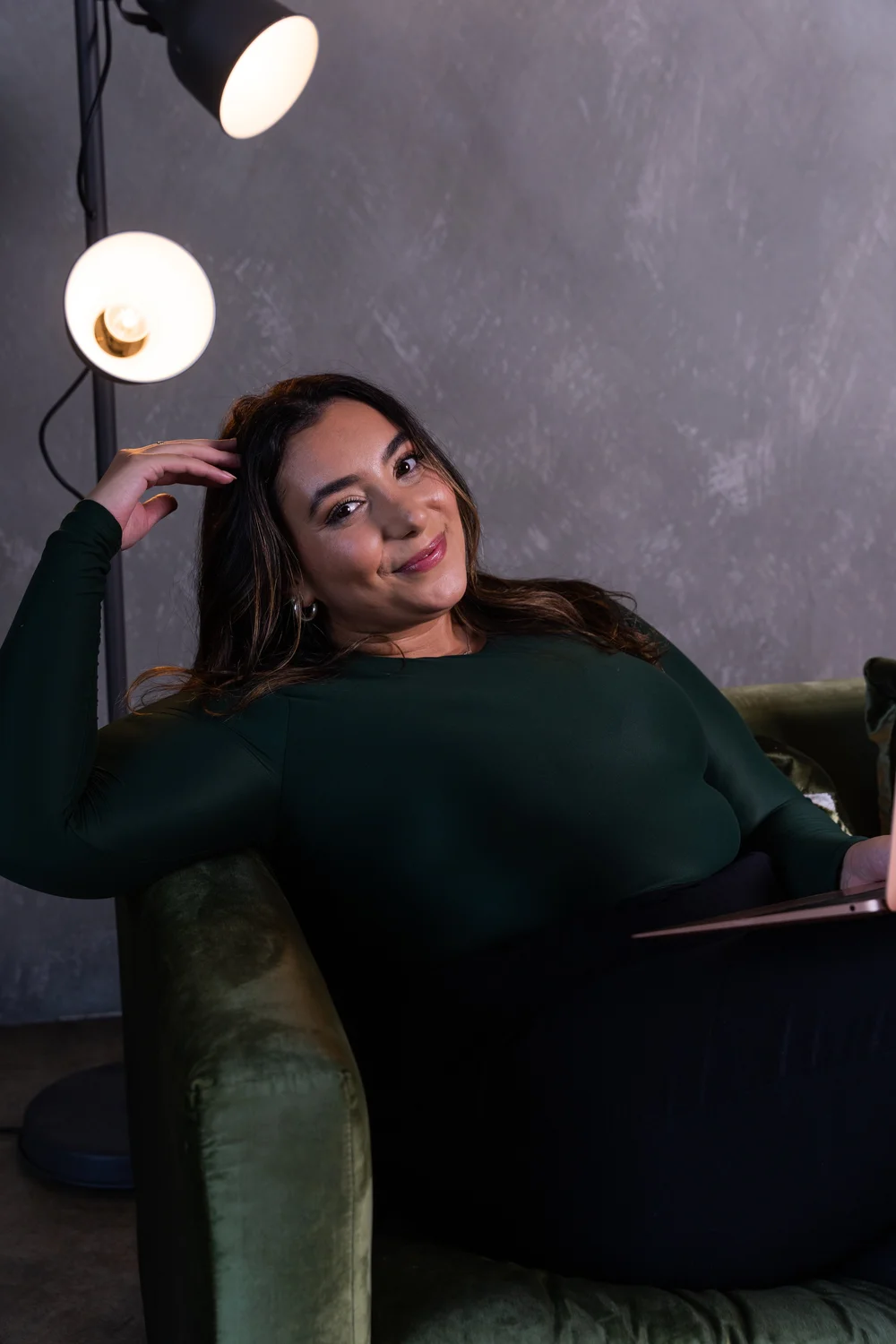 Avita seated in a green velvet armchair
