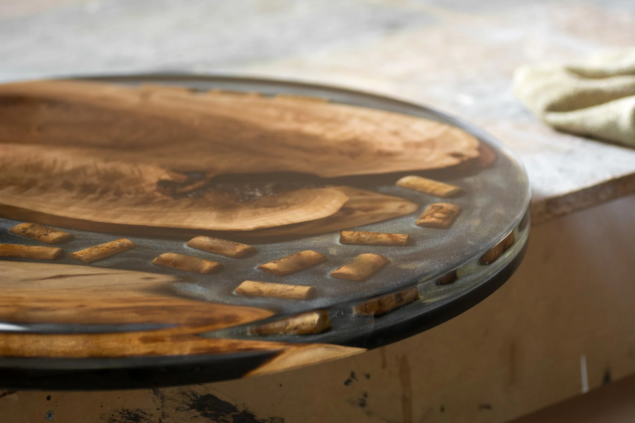 Close-up of a wooden and metal hot plate, with steam rising from it, positioned on a kitchen countertop with a beige cloth nearby.