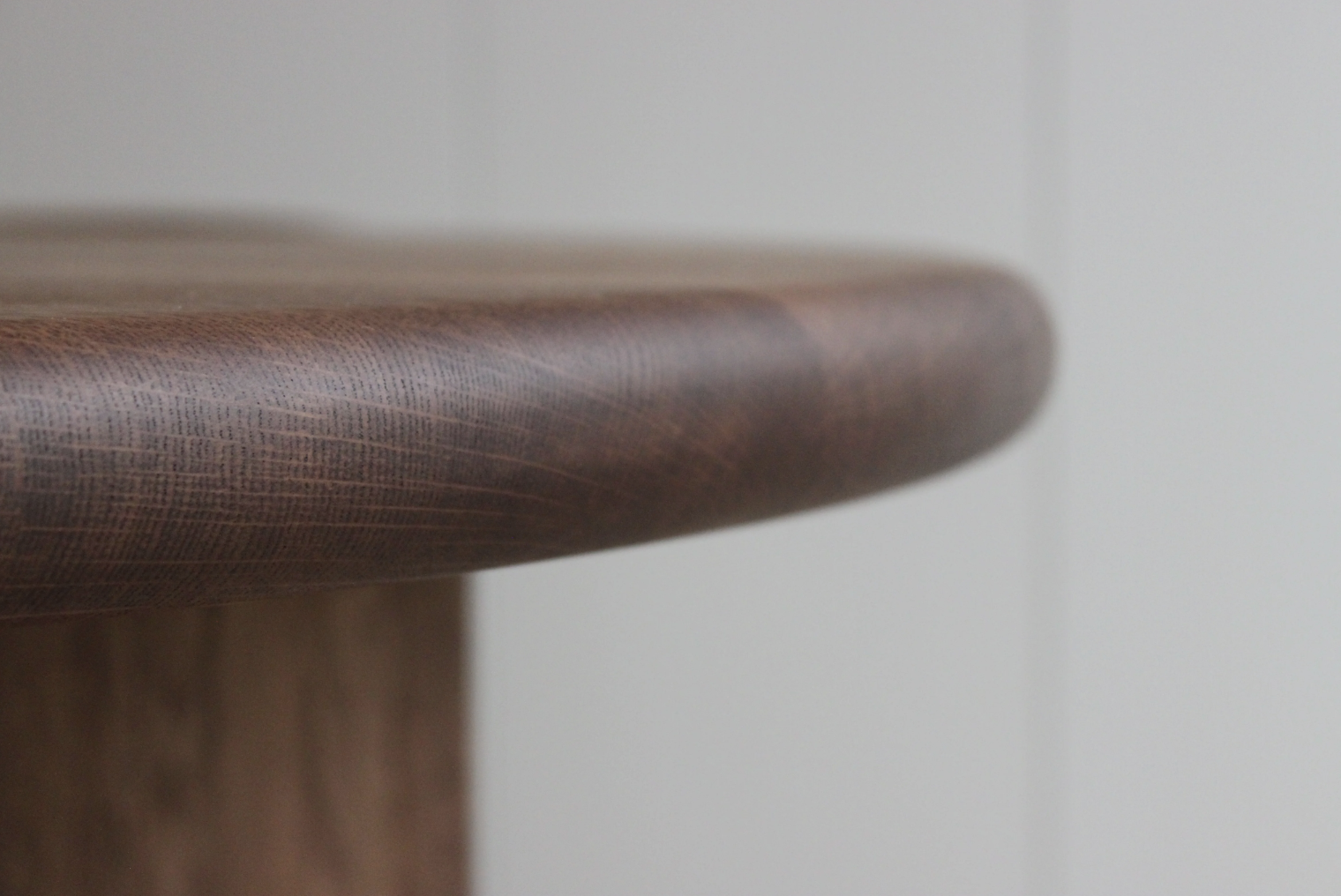 Close-up of the edge of a wooden table with a smooth, rounded corner and visible wood grain.