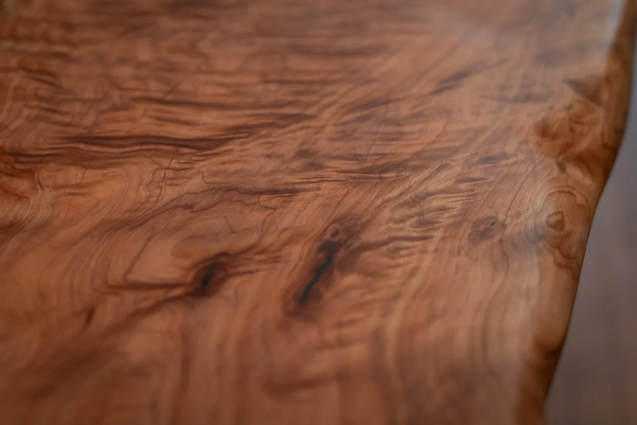 An extreme close-up of the timber bench surface, highlighting the intricate swirls and unique figure of the wood grain.