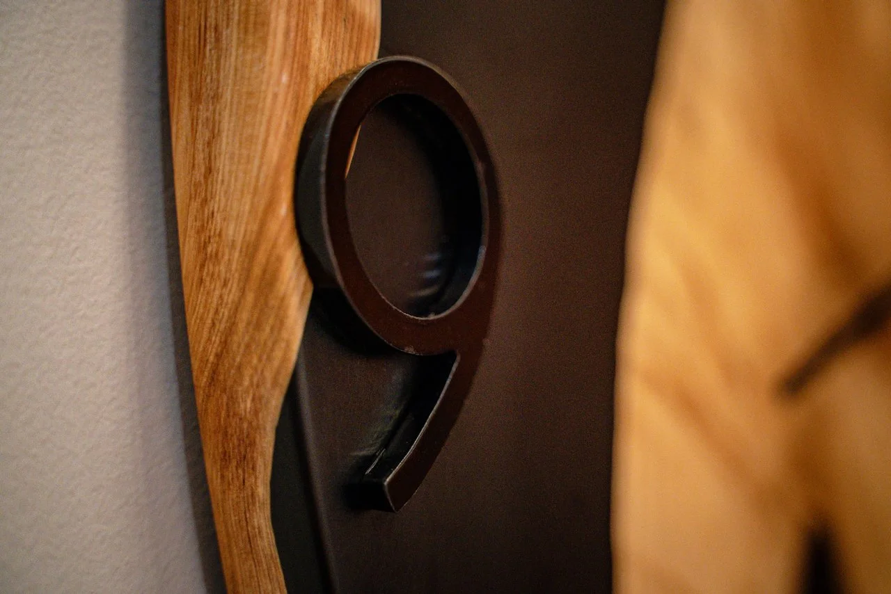 Metal clock number detail set against black epoxy and live edge Cypress Pine.