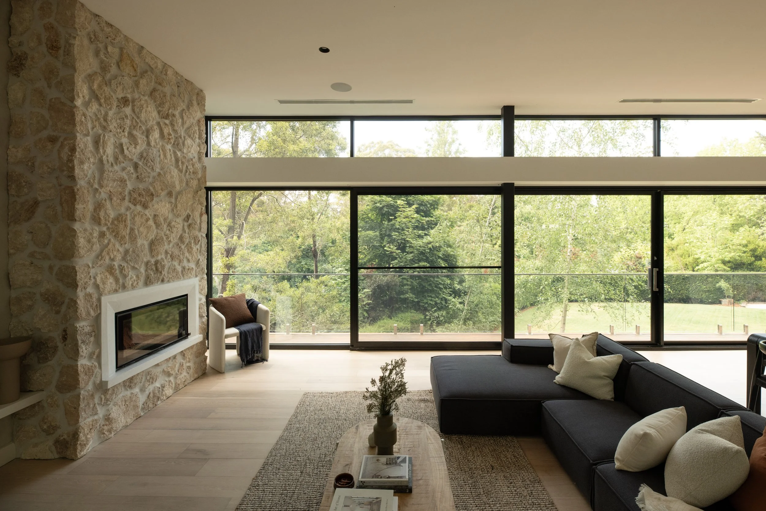 Living room with stone fireplace and floor-to-ceiling windows, full home interior design by Adelaide interior designer The Clarke Collection
