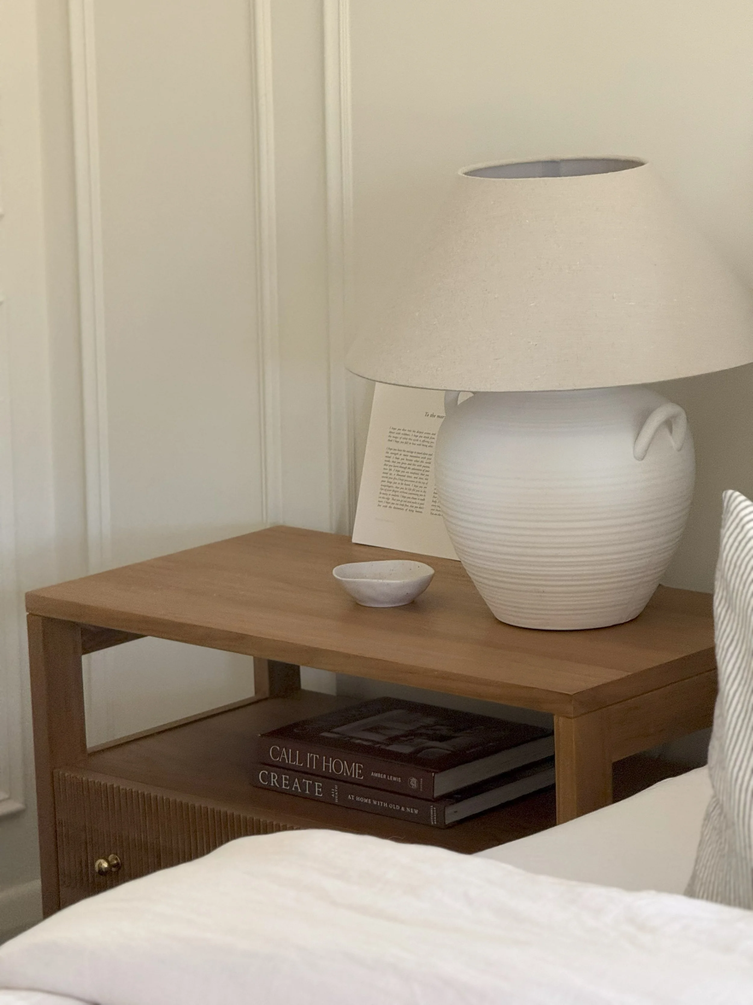 Bedside table with ceramic lamp in a calm, layered bedroom by Adelaide interior designer The Clarke Collection
