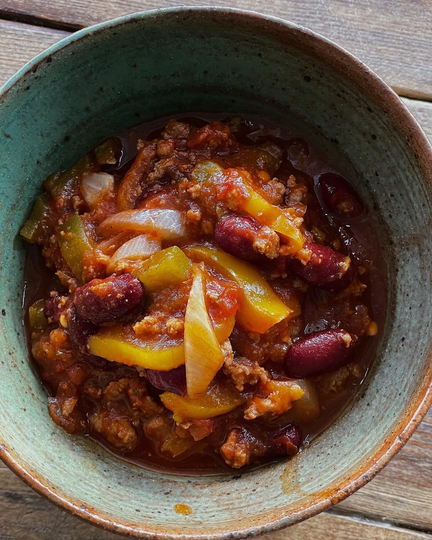 A bowl of sweet and spicy turkey chili with chopped bell peppers and red kidney beans.