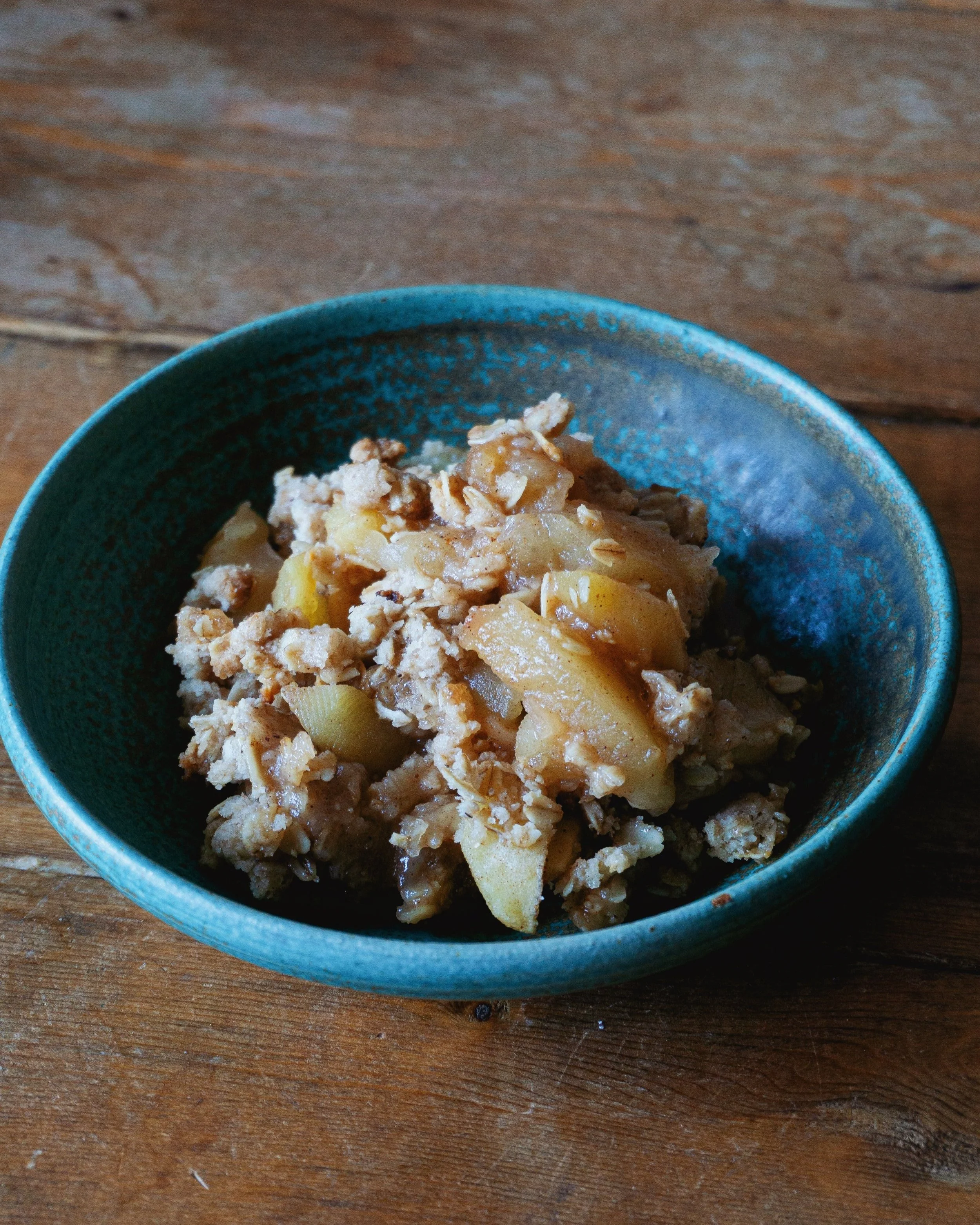 Delicious homemade apple crisp dessert in a white ceramic bowl.