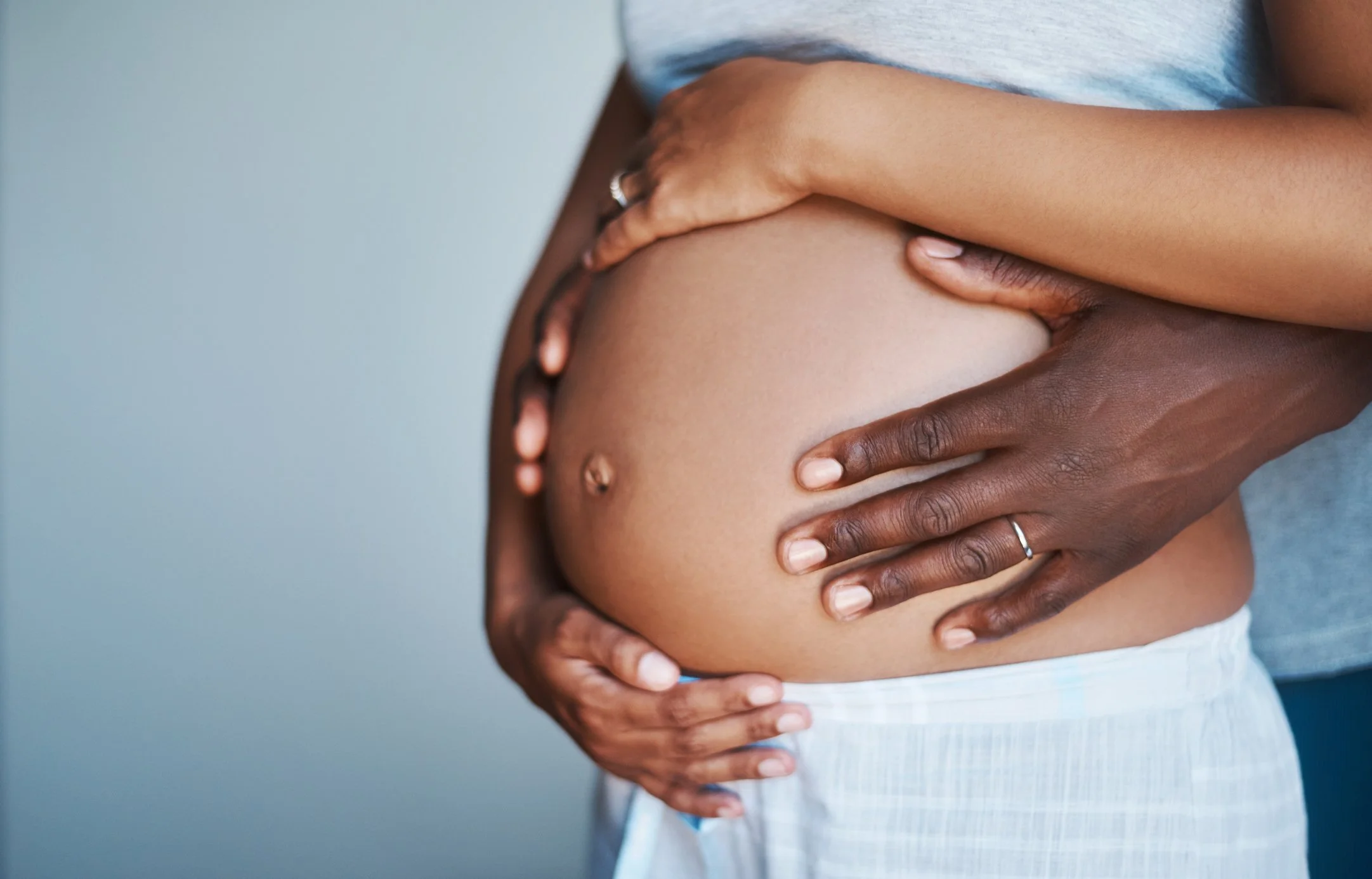 Pregnant couple using touch to support and reassure. At Drift Holistic Massage, I will help you feel comfortable and supported in your pregnancy journey.