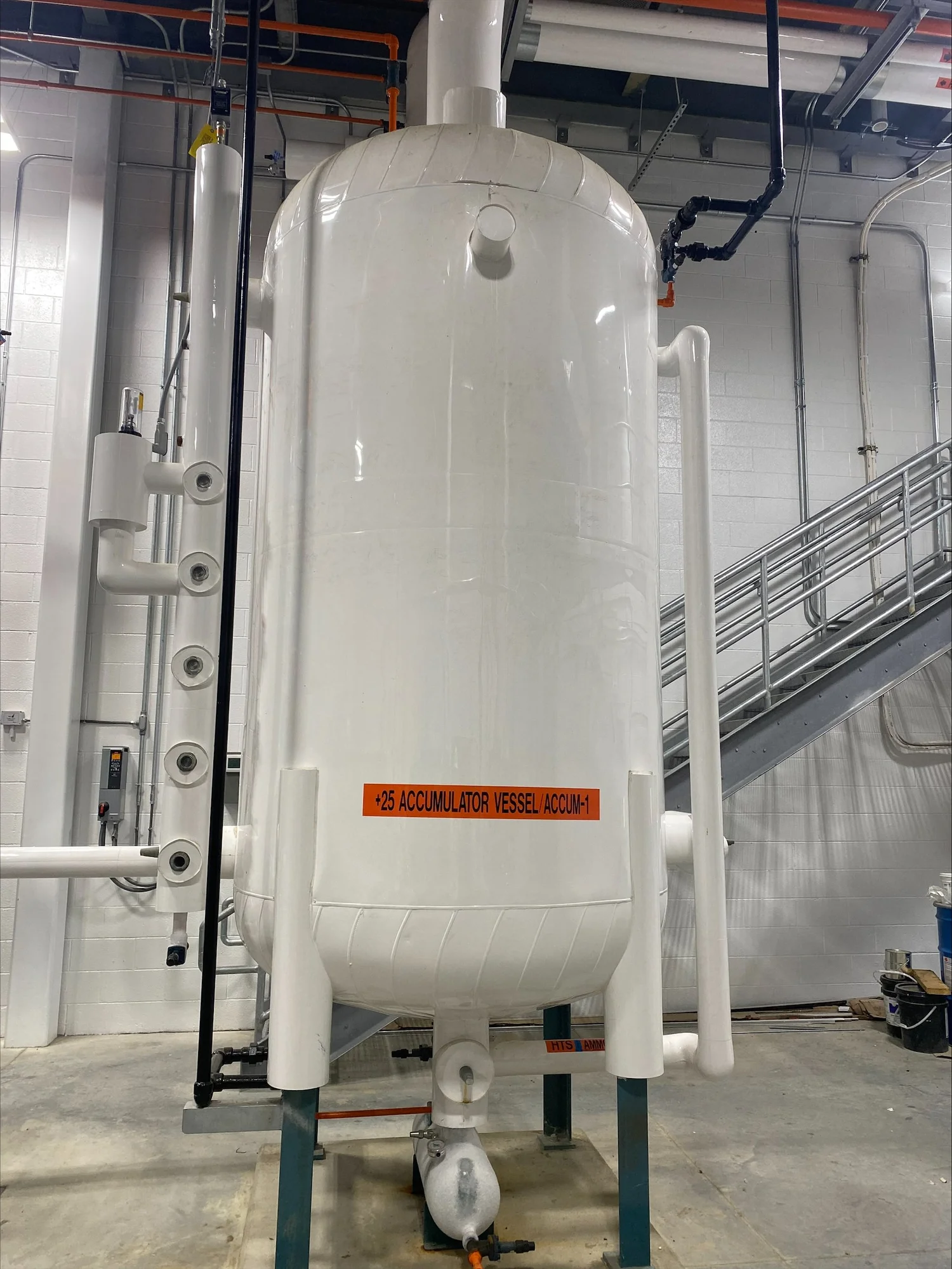 Insulated white process vessel with insulated piping inside a beverage bottling facility