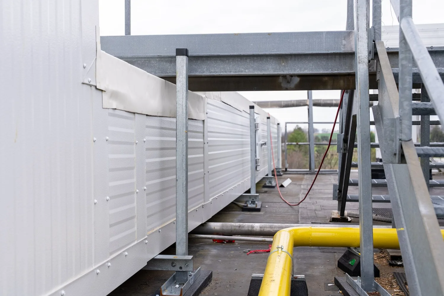 Rooftop insulated duct run and yellow gas piping on steel supports